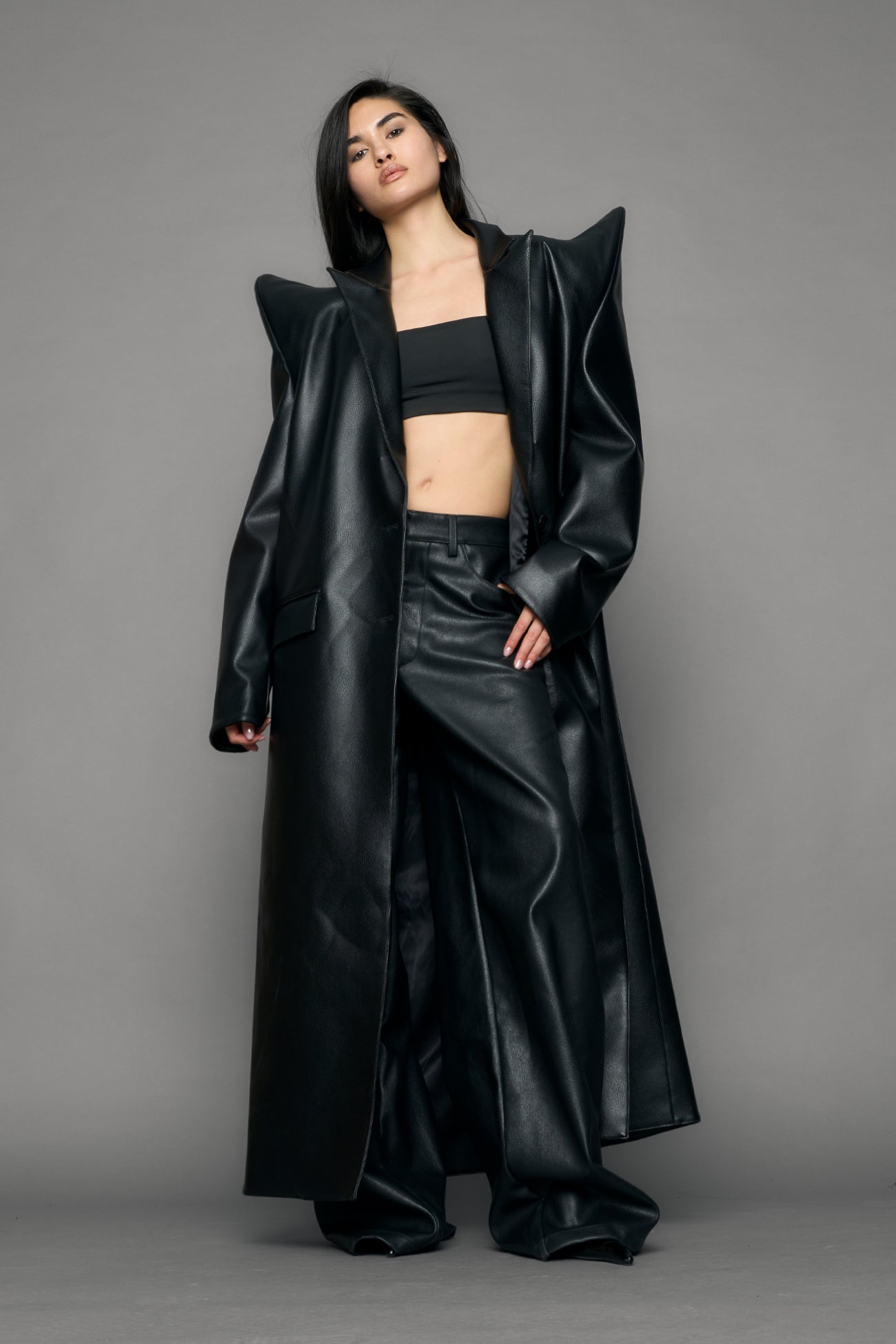 model wearing black pu leather coat with sharp shoulder design