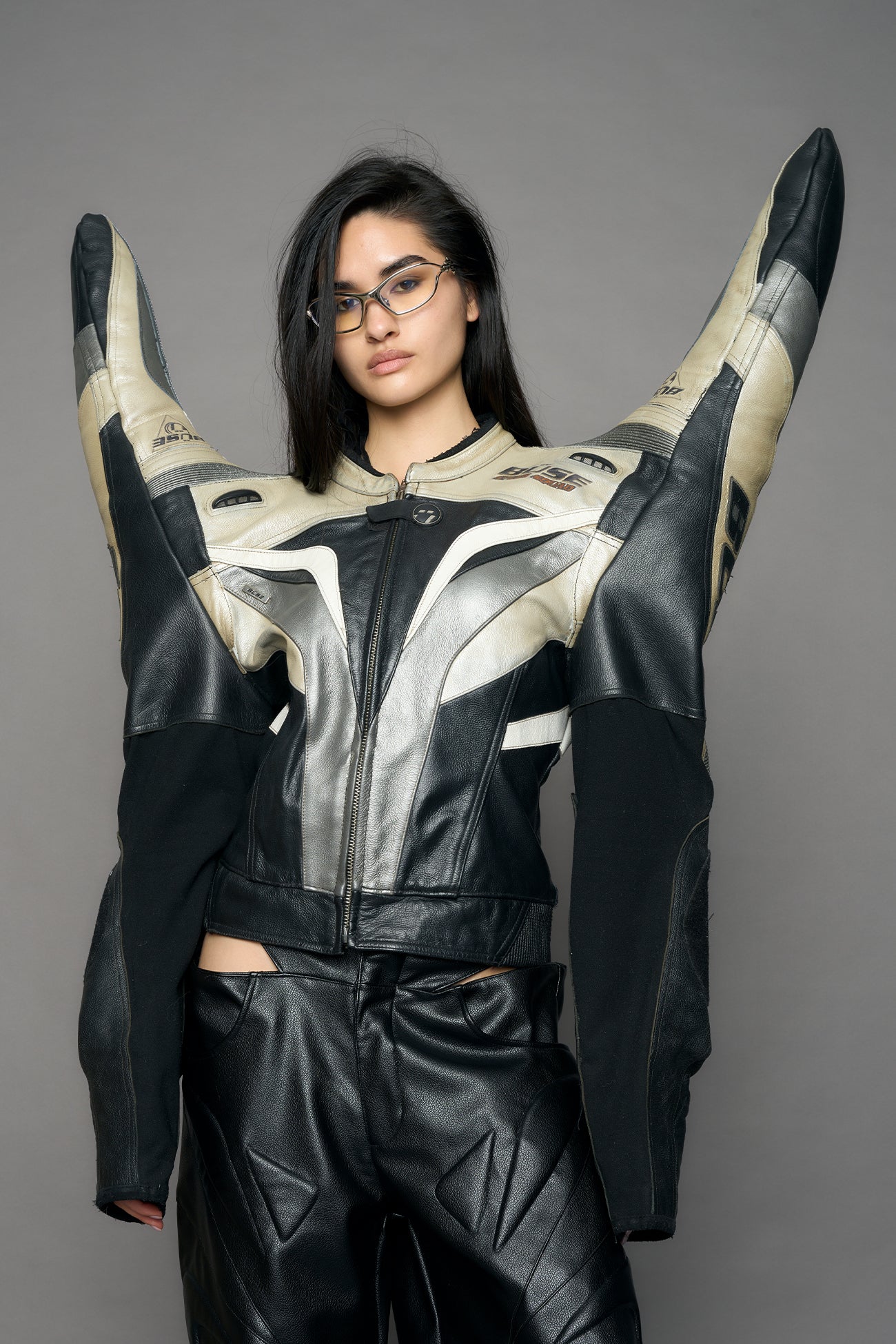 model wearing a motocross jacket with silver and black accents on a gray background