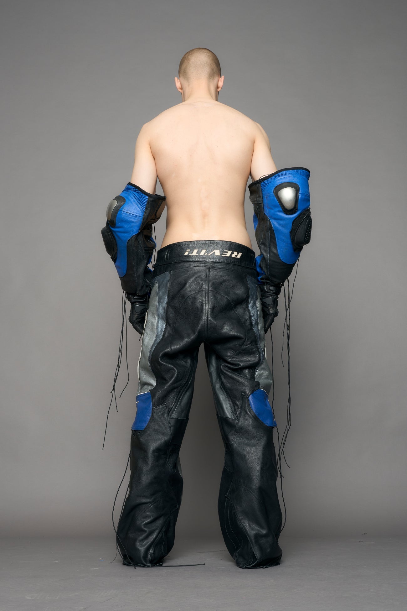 model wearing a motocross pants with silver and black accents on a gray background