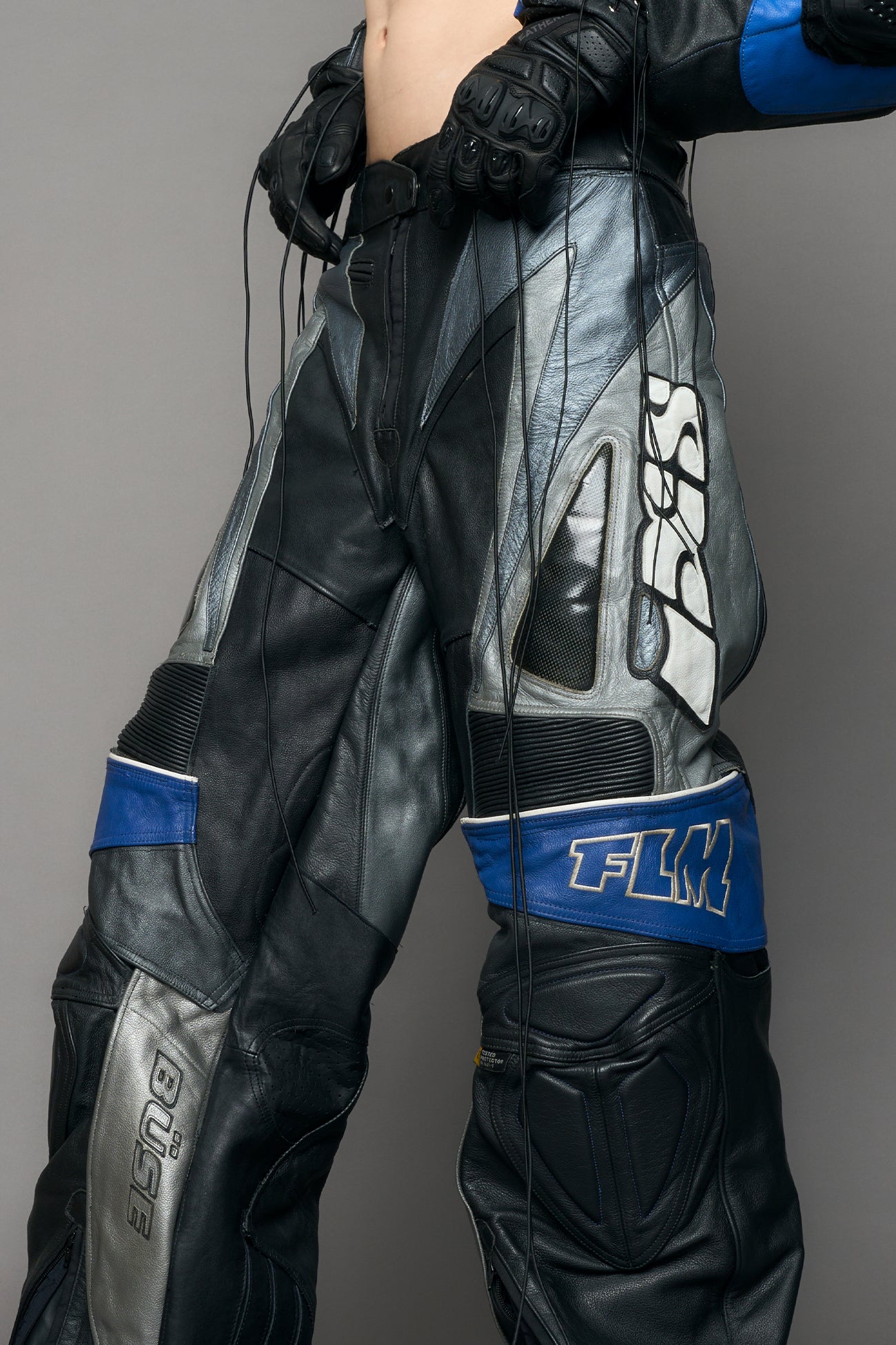 model wearing a motocross pants with silver and black accents on a gray background