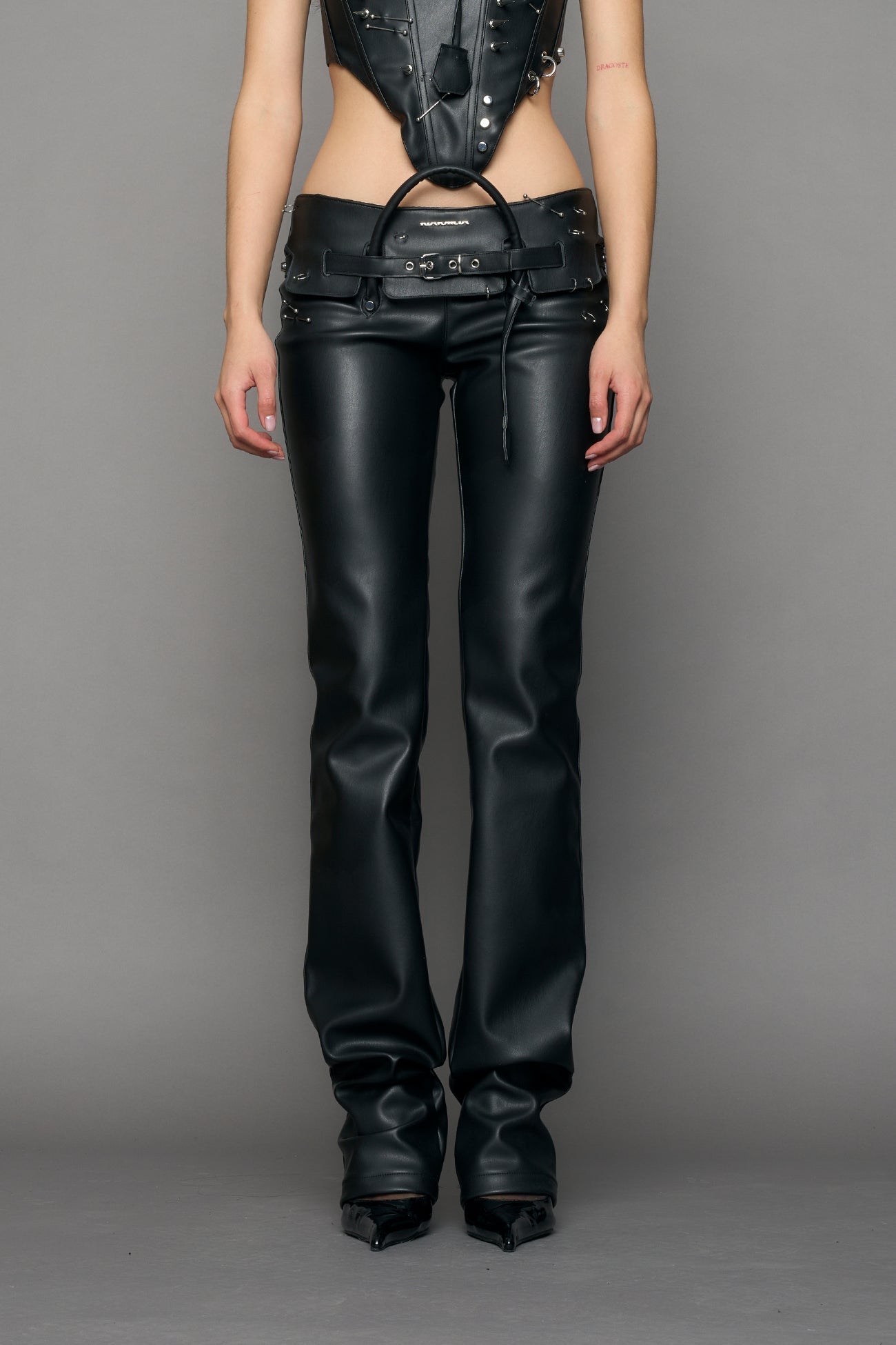 model wearing black pu leather studded handbag pants