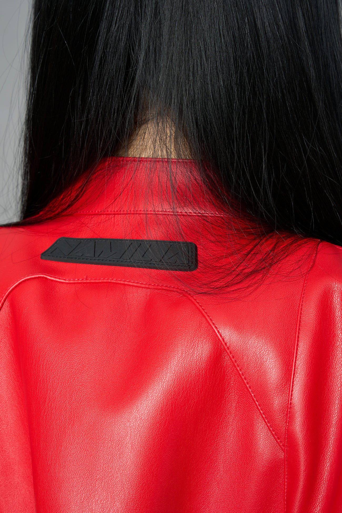 Model wears the red Namilia Spike Moto Bolero Jacket with wire shoulder pads, cropped hemline, branded front zipper, motocross-style lines, and black rubber logo tag on the back.