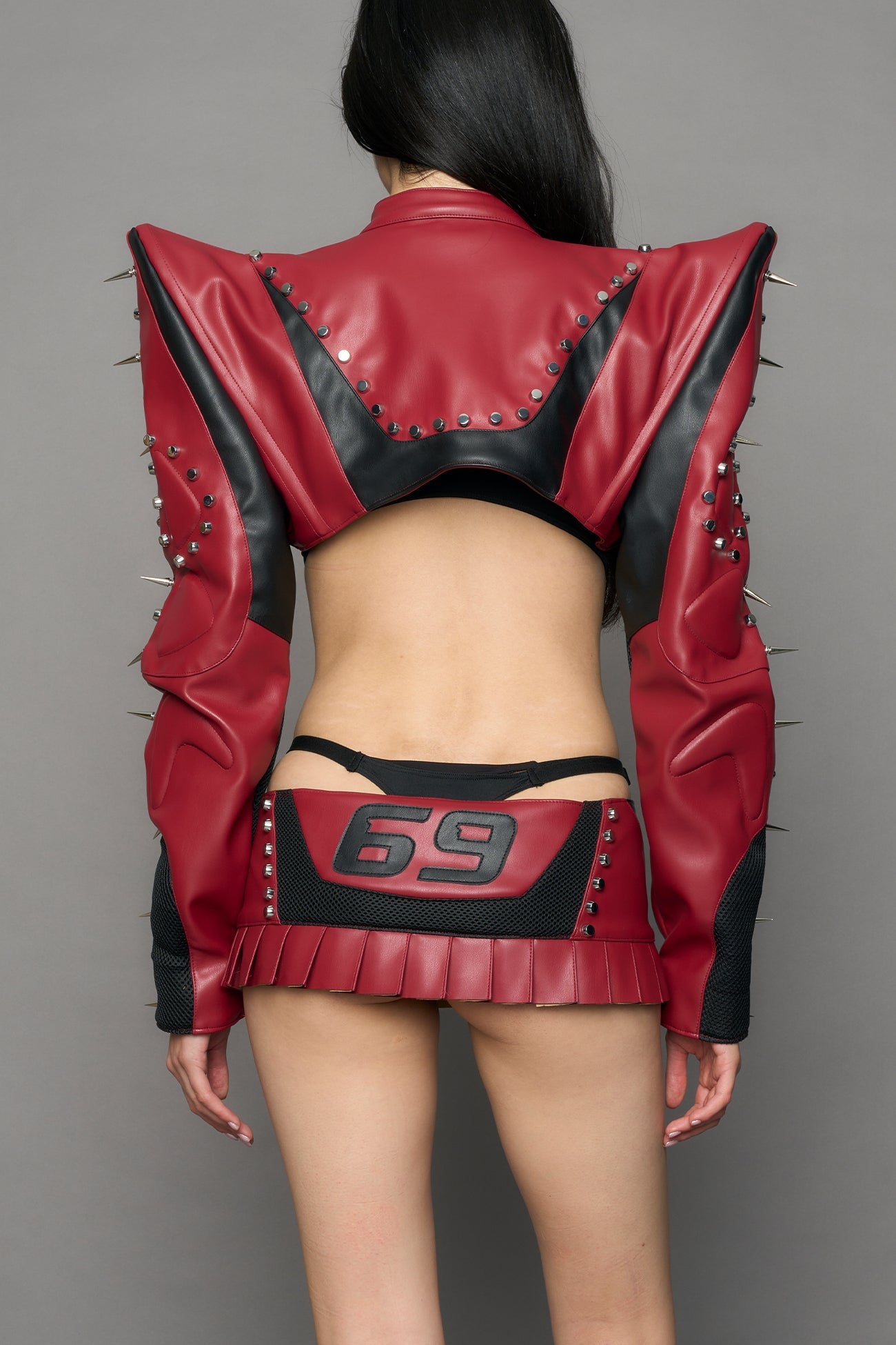 Model wearing a red studded leather choker jacket with cut-out design