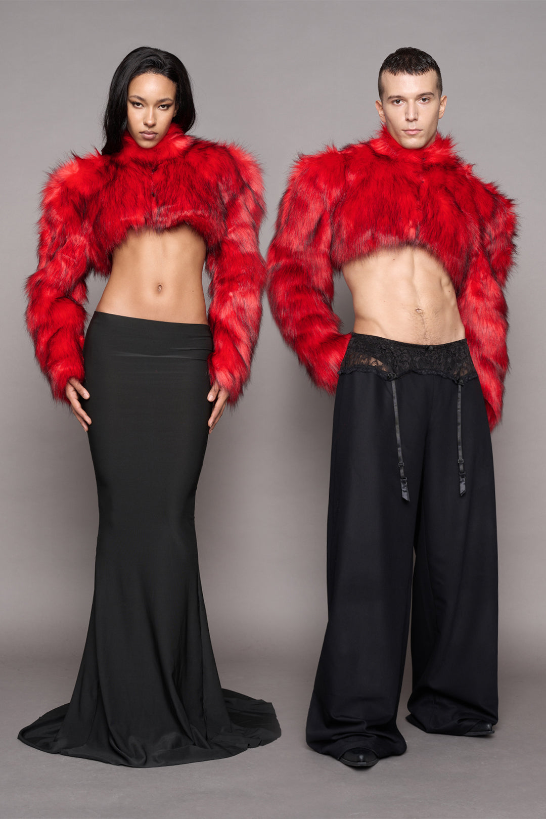 Two models wearing a matching red faux fur bolder with a high collar, styled in a long black skirt and a baggy black suiting pants