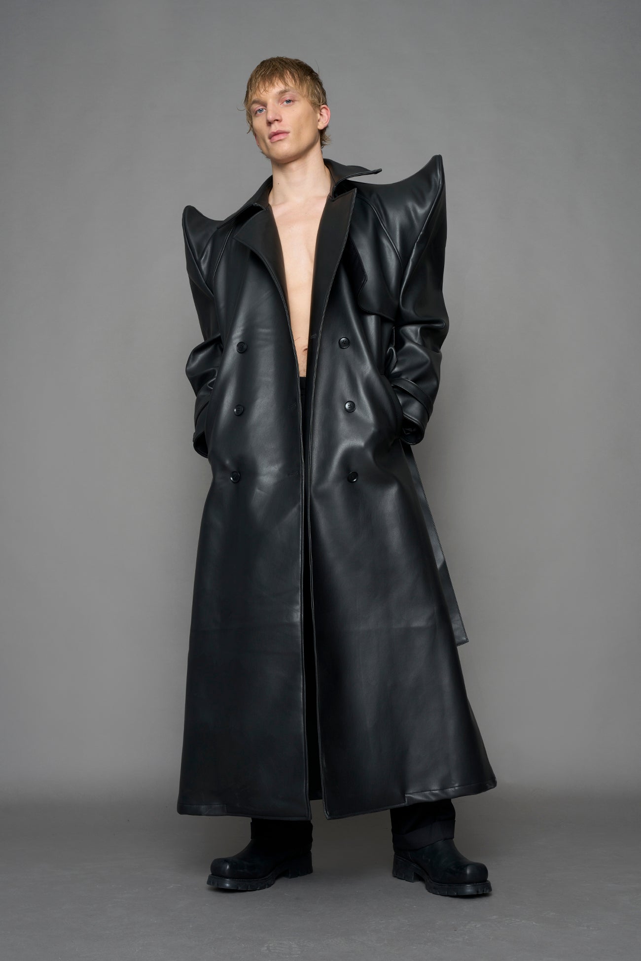 model wearing black vegan leather trench coat with sharp shoulder design