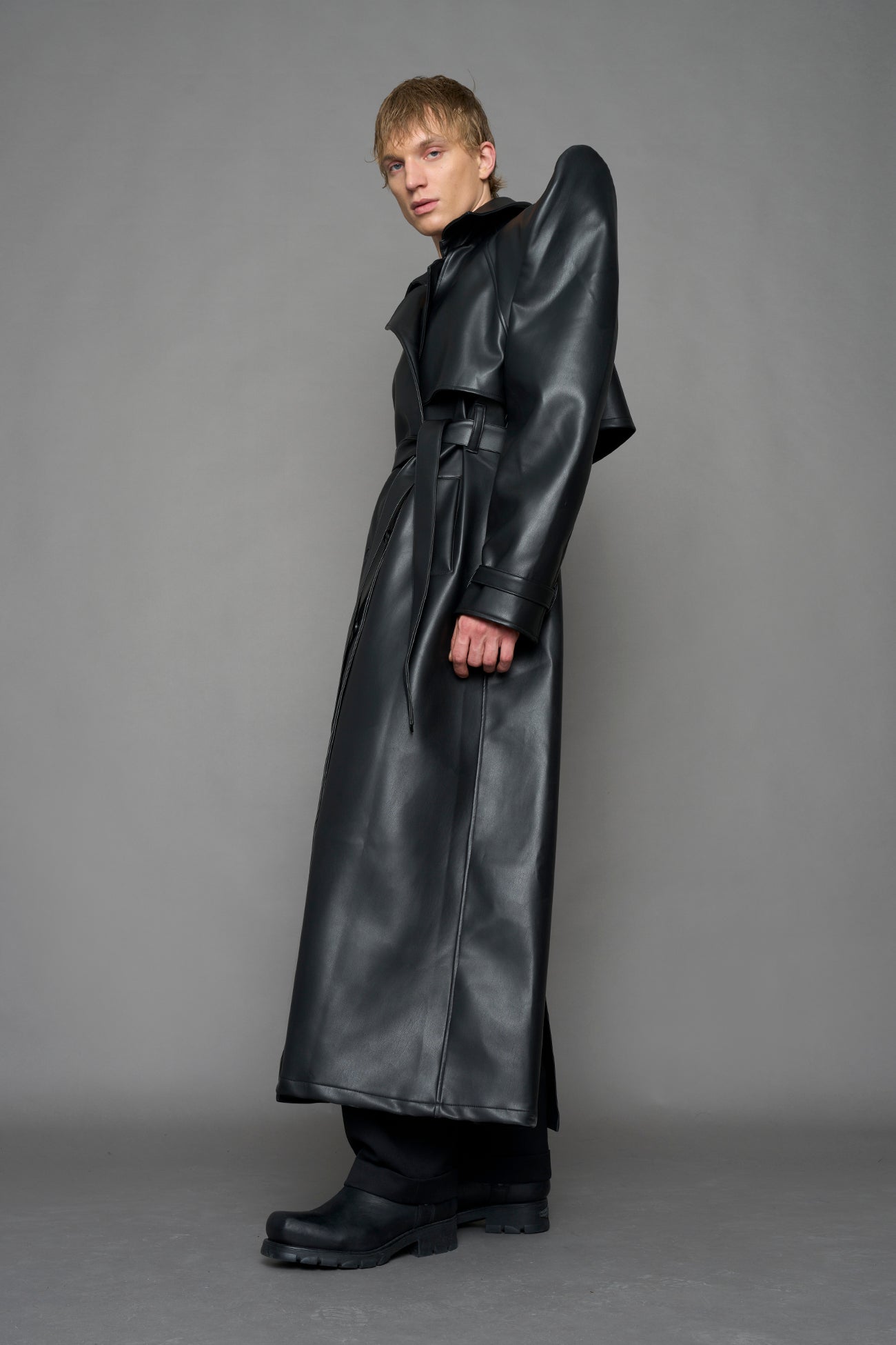 model wearing black vegan leather trench coat with sharp shoulder design