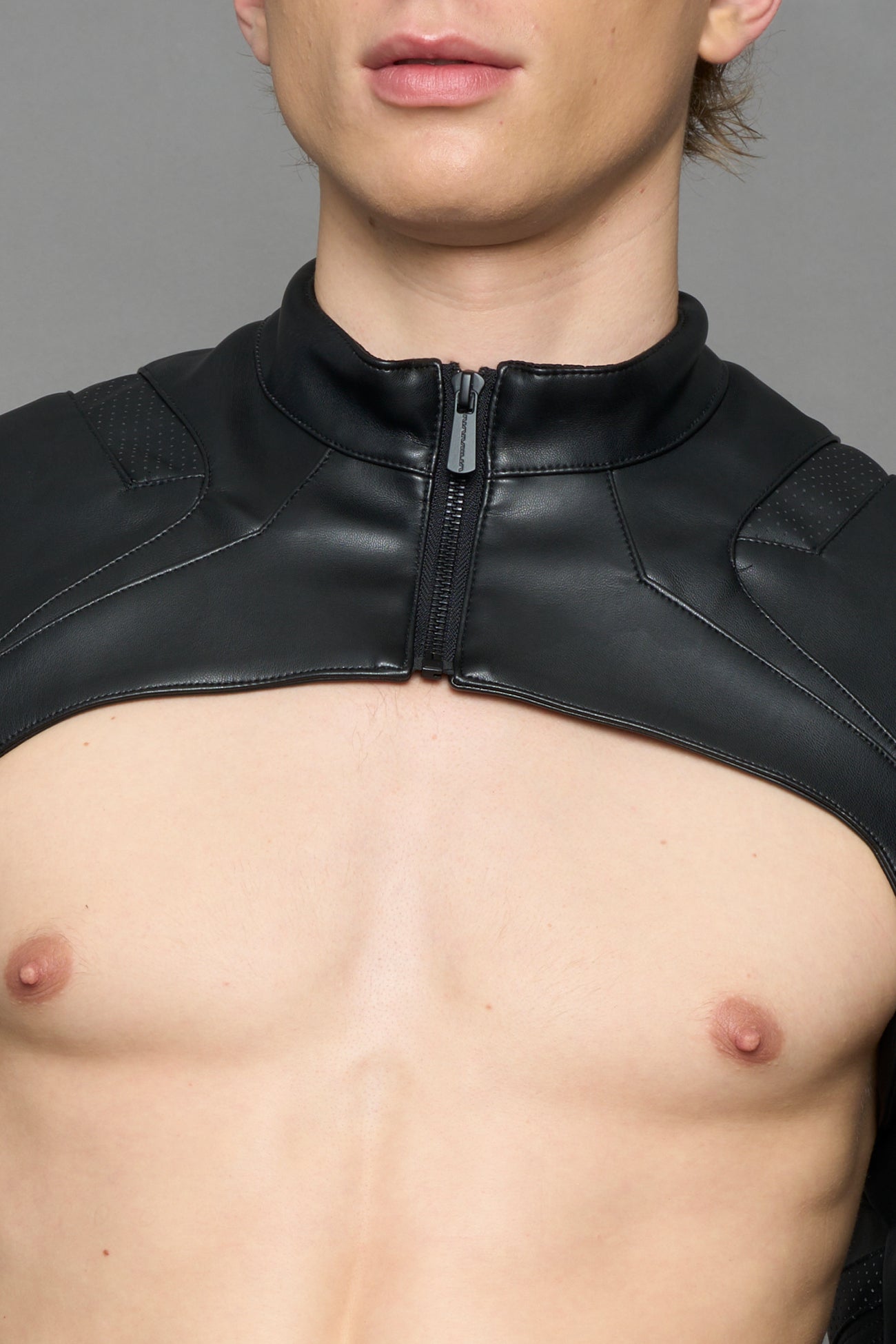 Close-up of a person's torso wearing a black faux-leather sleeve or jacket section with a large white diagonal logo