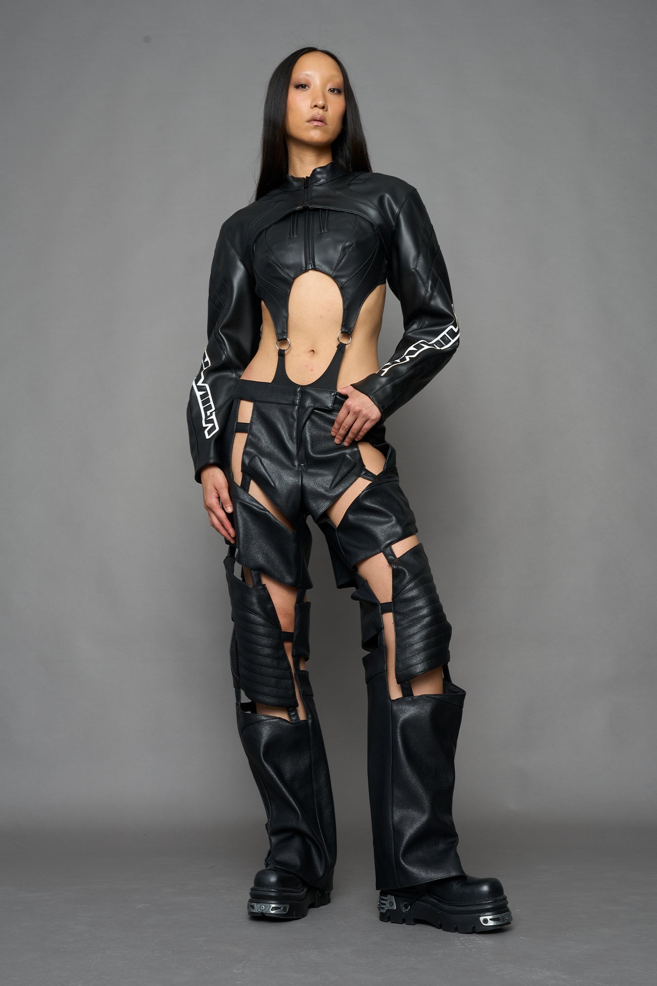 A model wearing a black faux-leather jacket with logo on the arm
