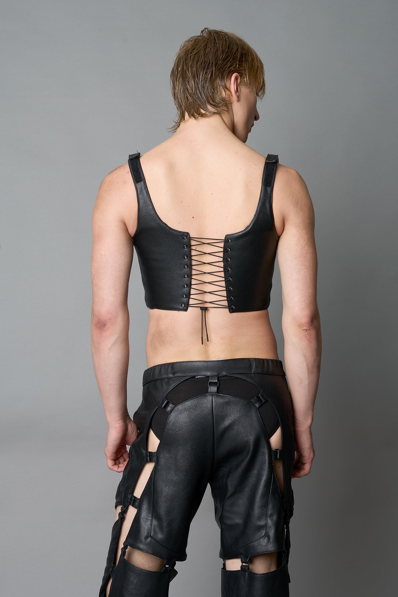 Model wearing black vegan leather XTC Corset by Namilia featuring extreme plunging neckline, front lace-up closure, and sculpted fit