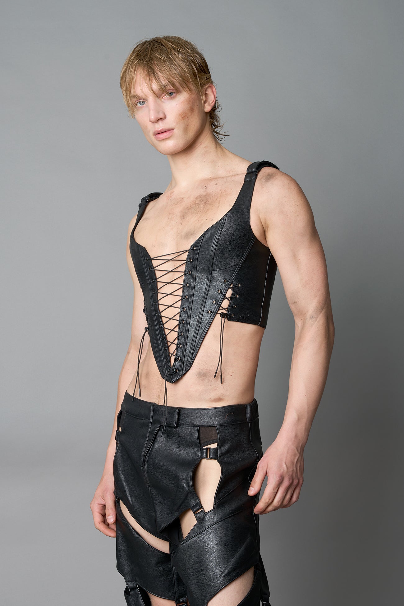 Model wearing black vegan leather XTC Corset by Namilia featuring extreme plunging neckline, front lace-up closure, and sculpted fit