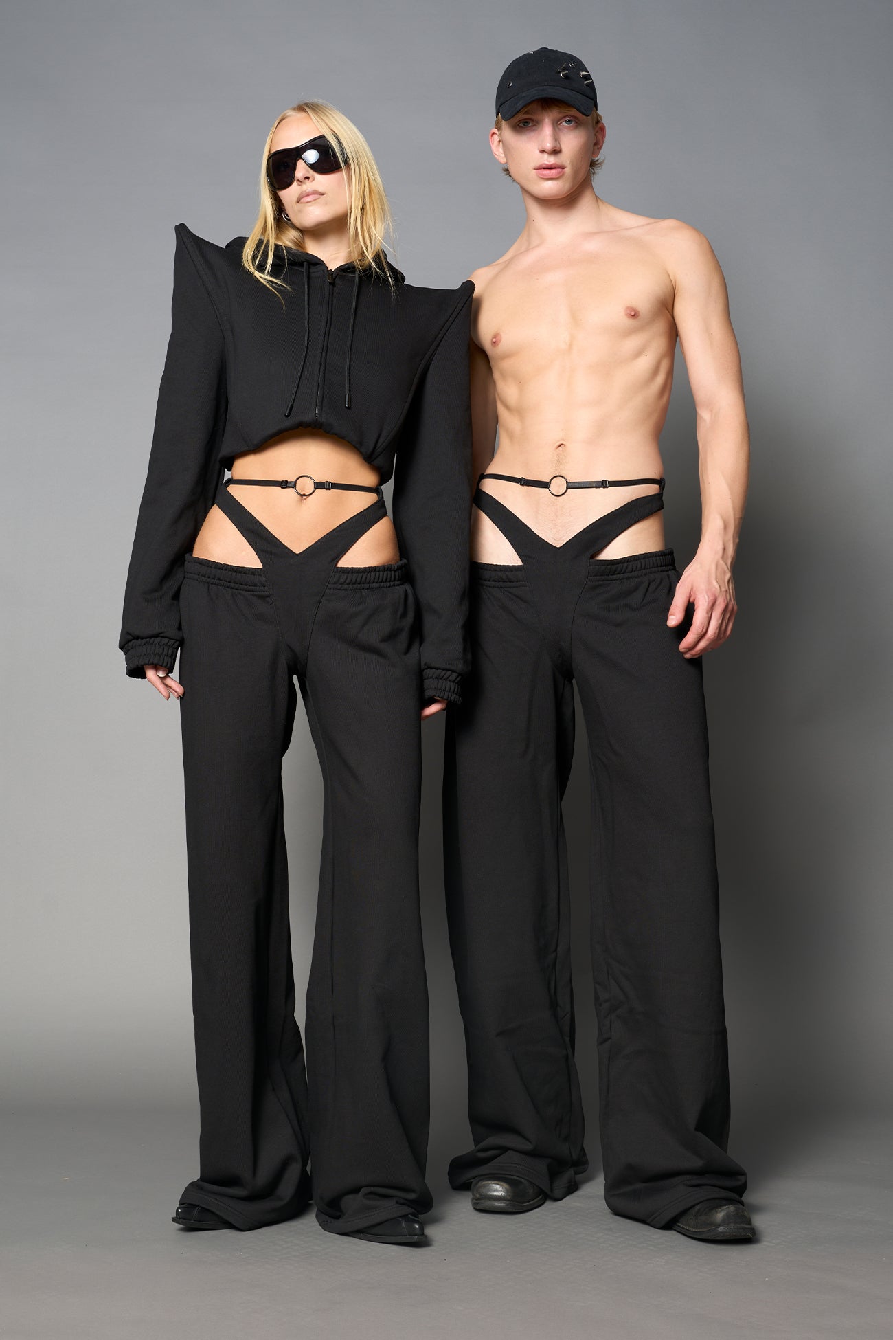 Model wearing low-rise black wide-leg pants featuring a V-shaped waistband and detachable thong strap detail.