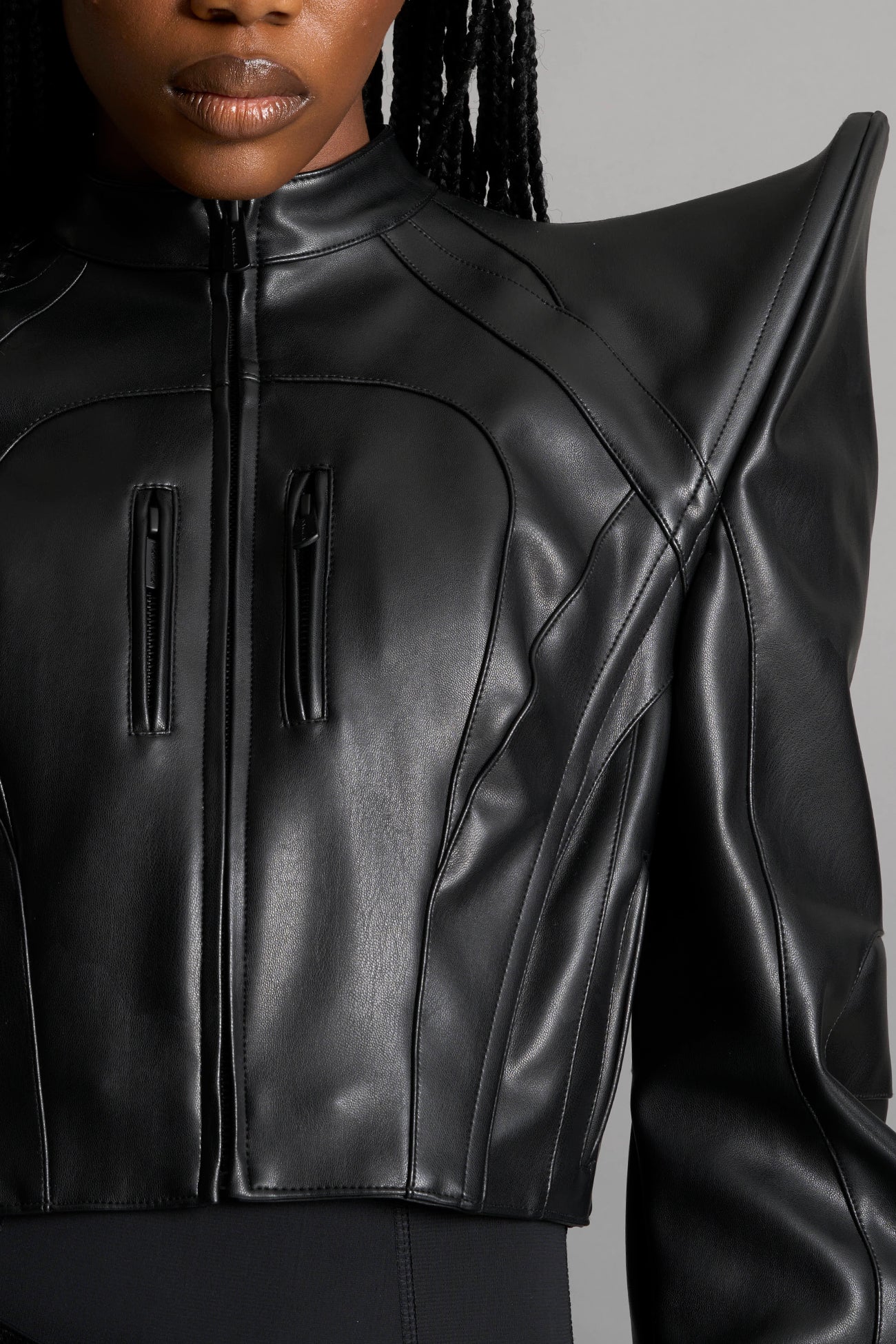 Model wears the black Namilia Spike Moto Jacket with wire shoulder pads, branded zipper, band collar, zippered breast and waist pockets, motocross-style lines, and black logo rubber tag on the back.