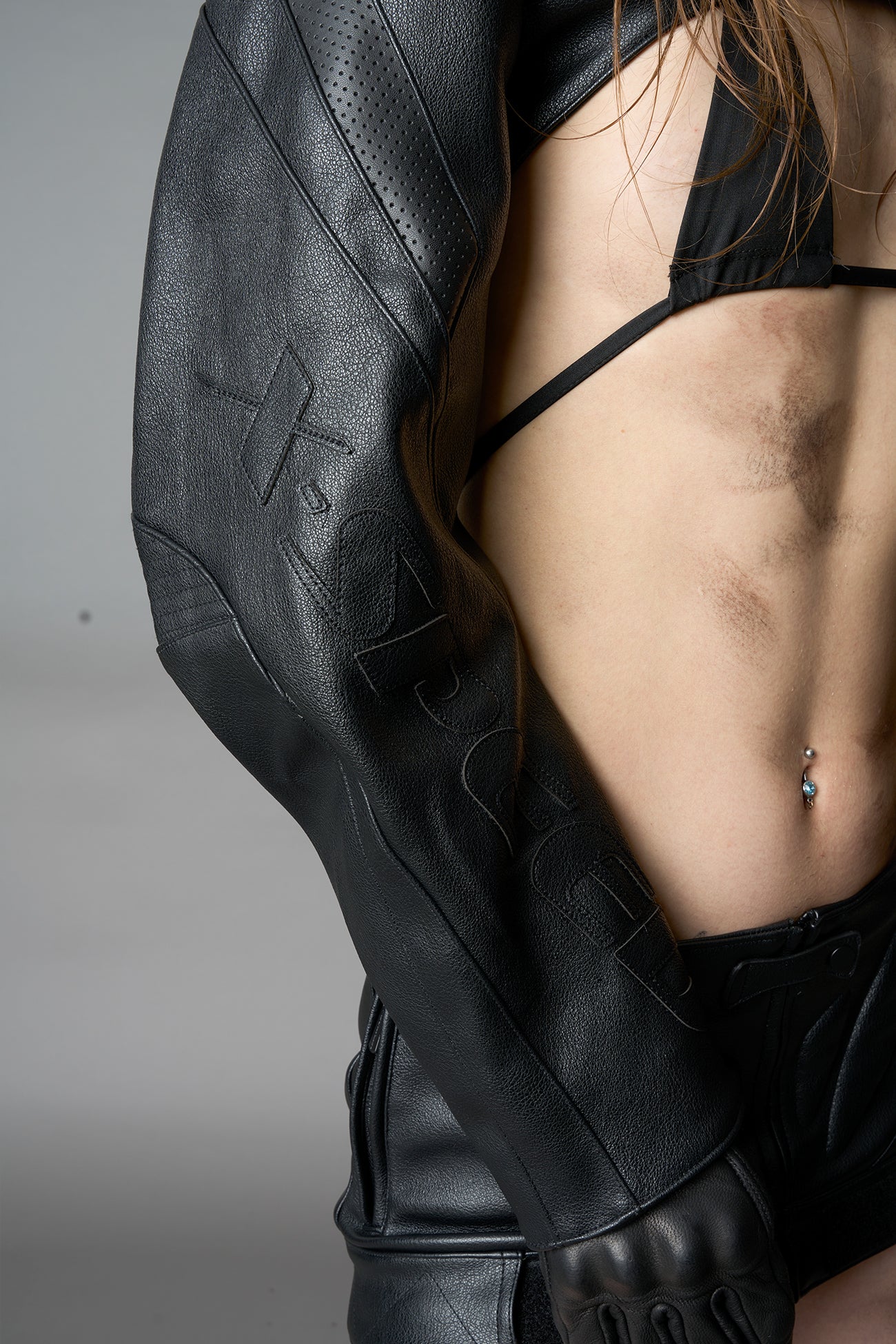 Model wearing a black vegan leather cropped jacket with a high choker collar and zipper front