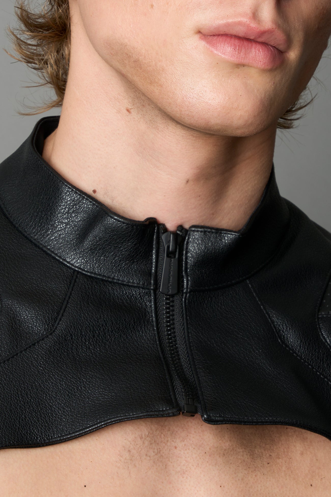 Model wearing a black vegan leather cropped jacket with a high choker collar and zipper front