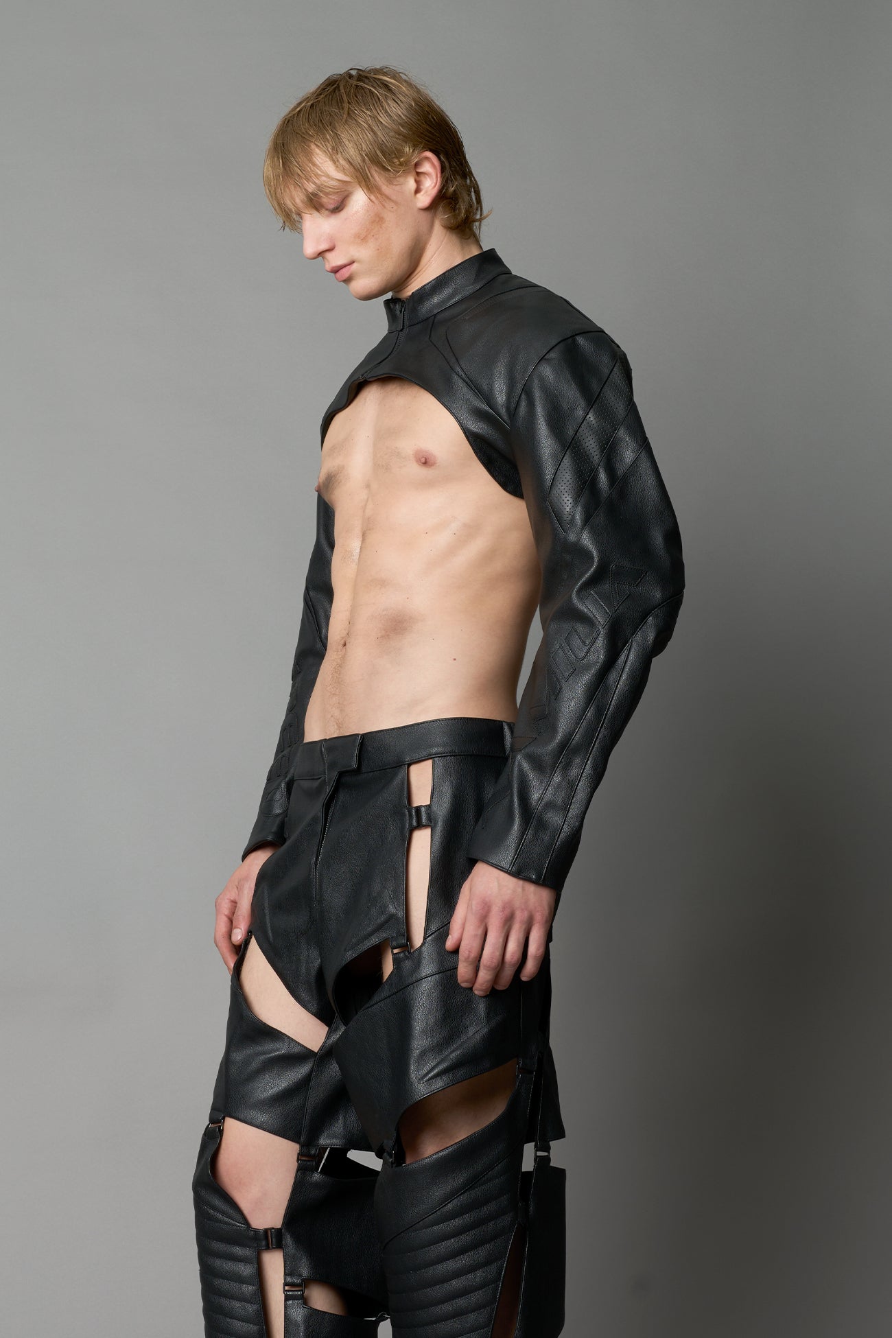Model wearing a black vegan leather cropped jacket with a high choker collar and zipper front