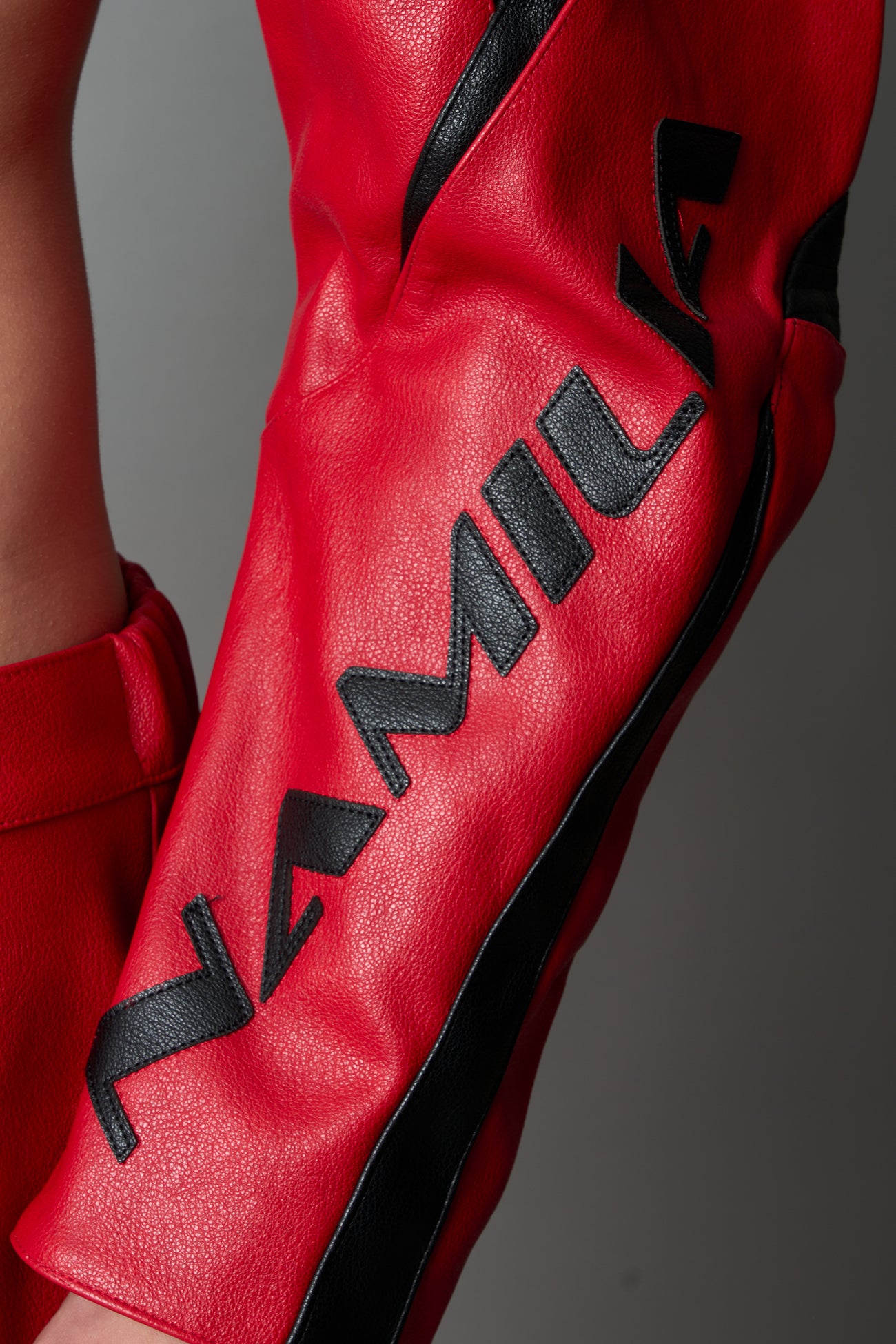 Model wearing a red vegan leather cropped jacket with a high choker collar and zipper front