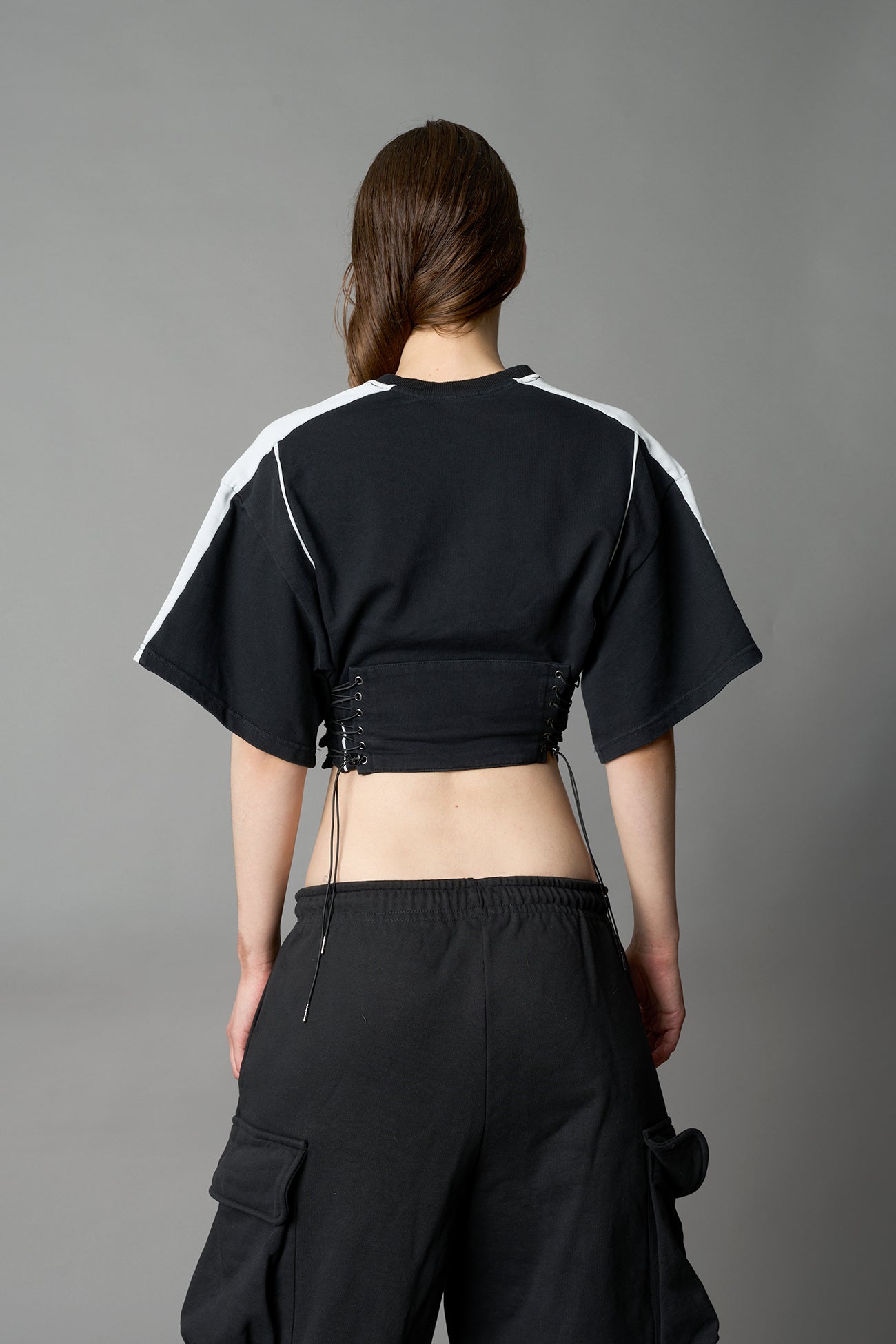 Front view of model in washed-black Namilia Corset-T shirt with sculpted corset-style waist, curved hemline, and oversized sleeves
