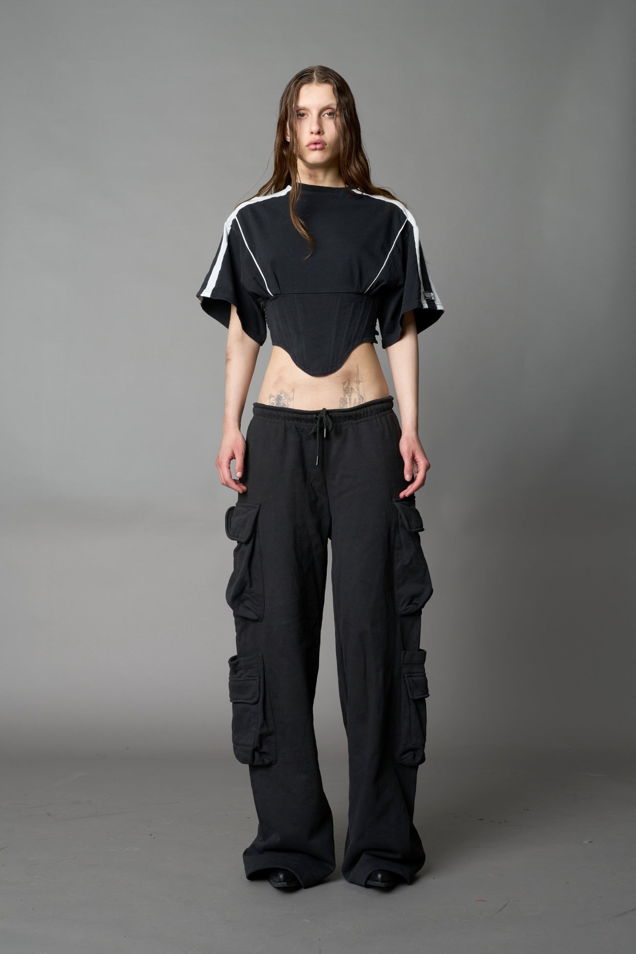 Front view of model in washed-black Namilia Corset-T shirt with sculpted corset-style waist, curved hemline, and oversized sleeves