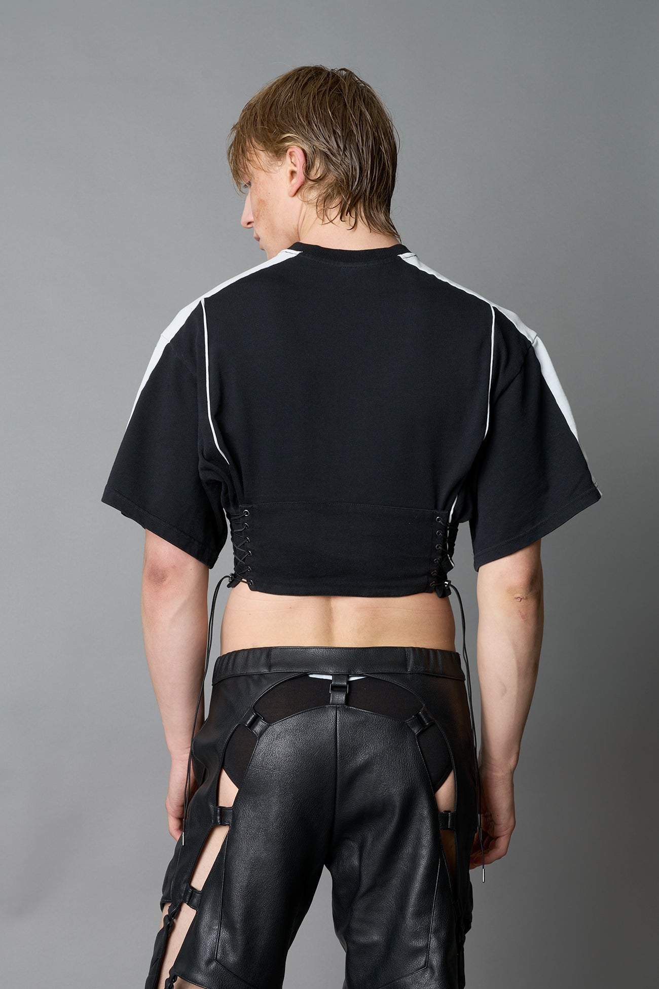 Front view of model in washed-black Namilia Corset-T shirt with sculpted corset-style waist, curved hemline, and oversized sleeves