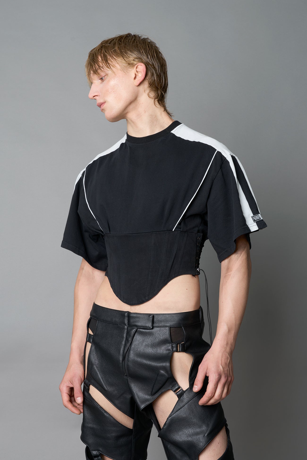 Front view of model in washed-black Namilia Corset-T shirt with sculpted corset-style waist, curved hemline, and oversized sleeves