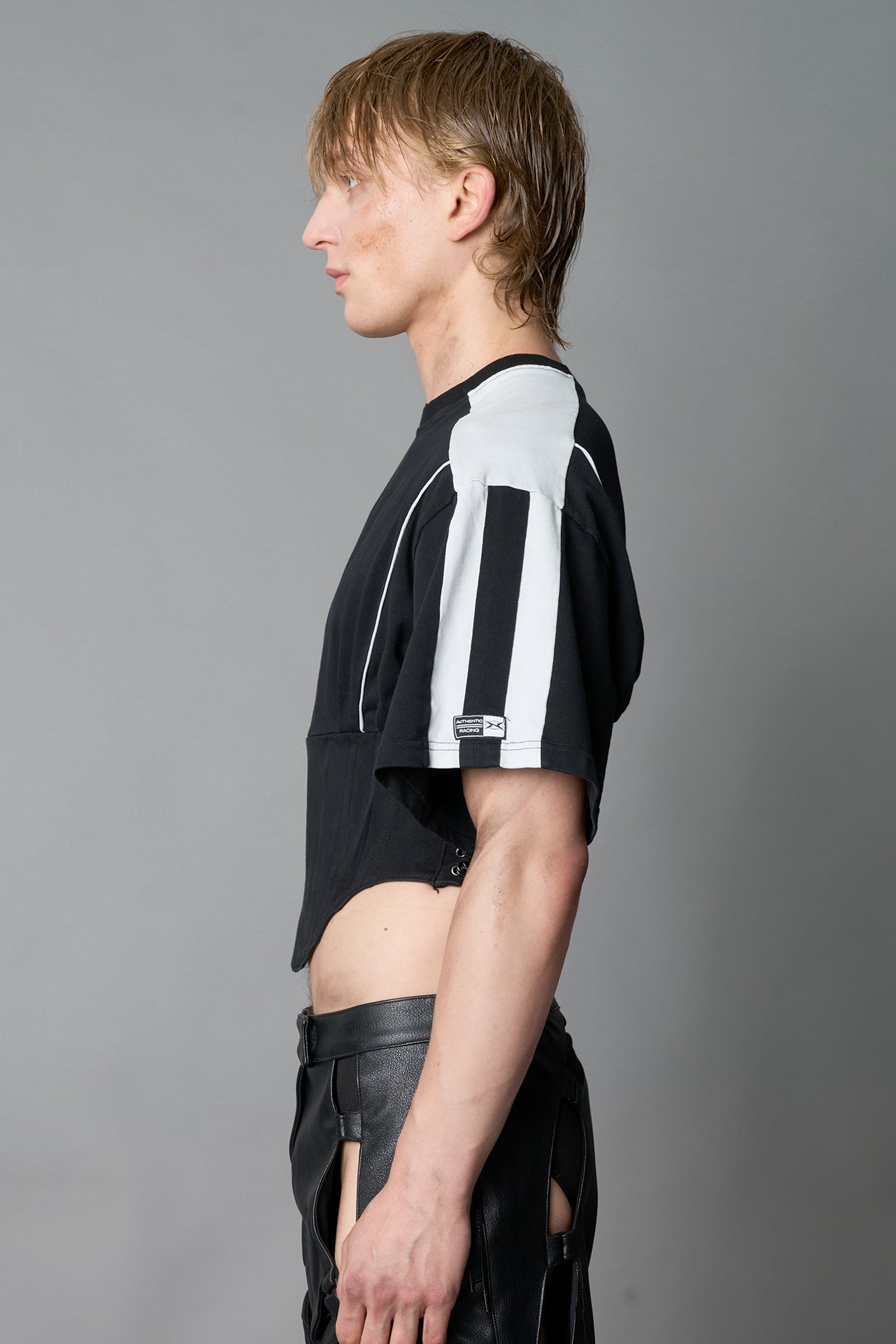 Front view of model in washed-black Namilia Corset-T shirt with sculpted corset-style waist, curved hemline, and oversized sleeves