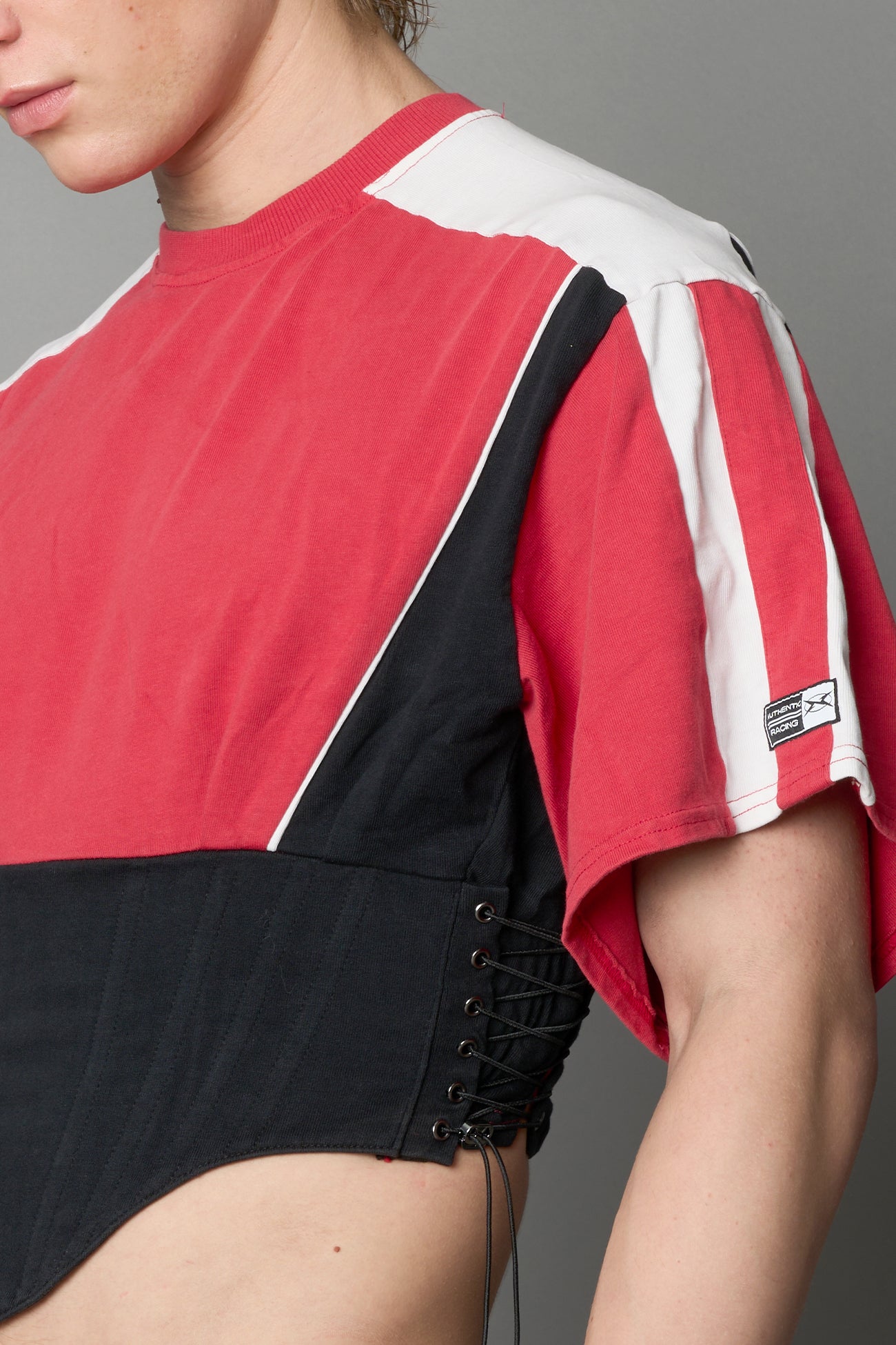 Front view of model in red Namilia Corset-T shirt with sculpted corset-style waist, curved hemline, and oversized sleeves,