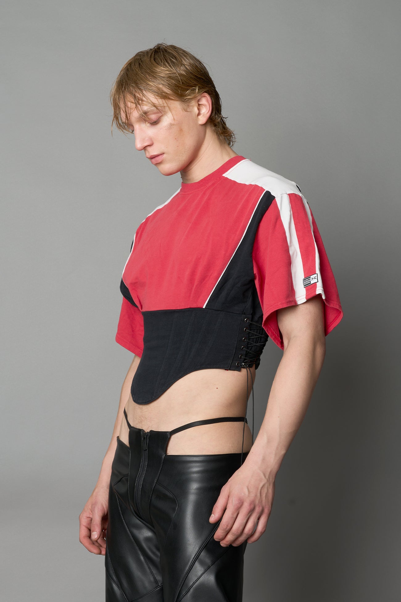 Front view of model in red Namilia Corset-T shirt with sculpted corset-style waist, curved hemline, and oversized sleeves,