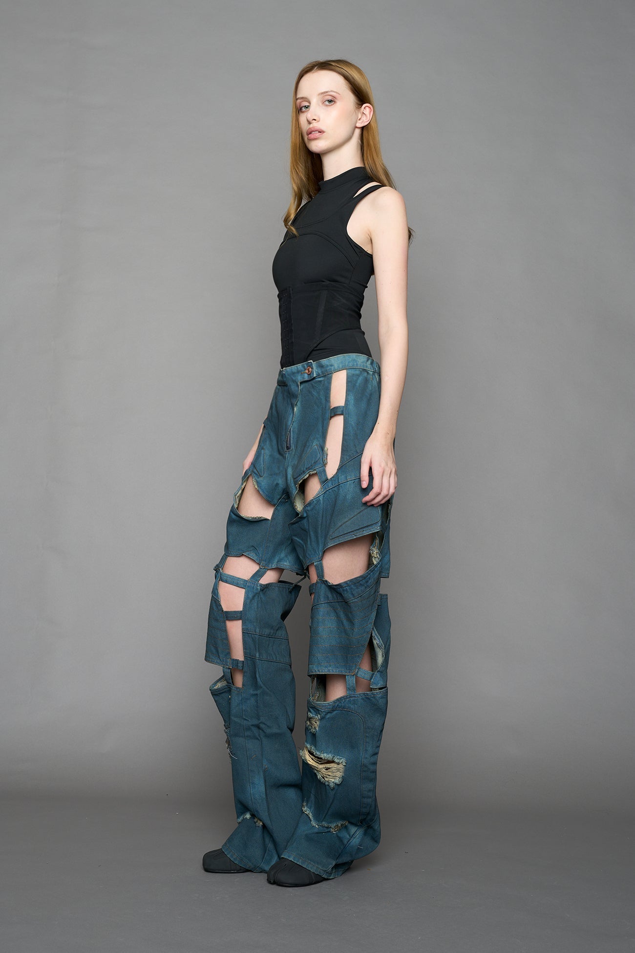 model wearing blue smoke denim pants with motocross inspired cut outs