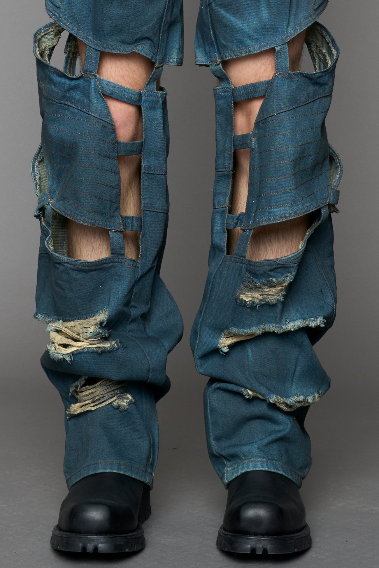 model wearing blue smoke denim pants with motocross inspired cut outs