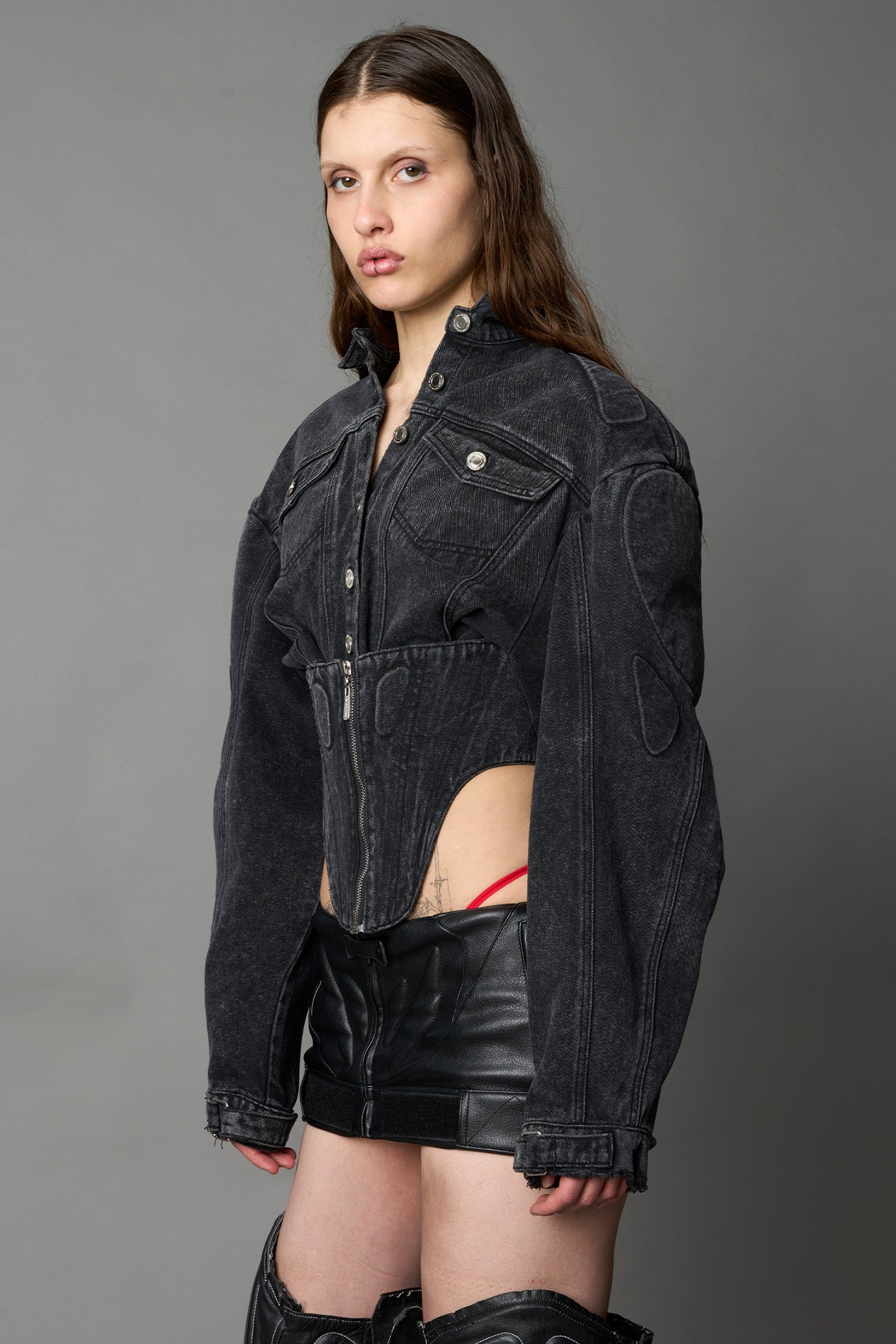 model wearing black washed denim jacket with structured corset waist and moto-style silhouette