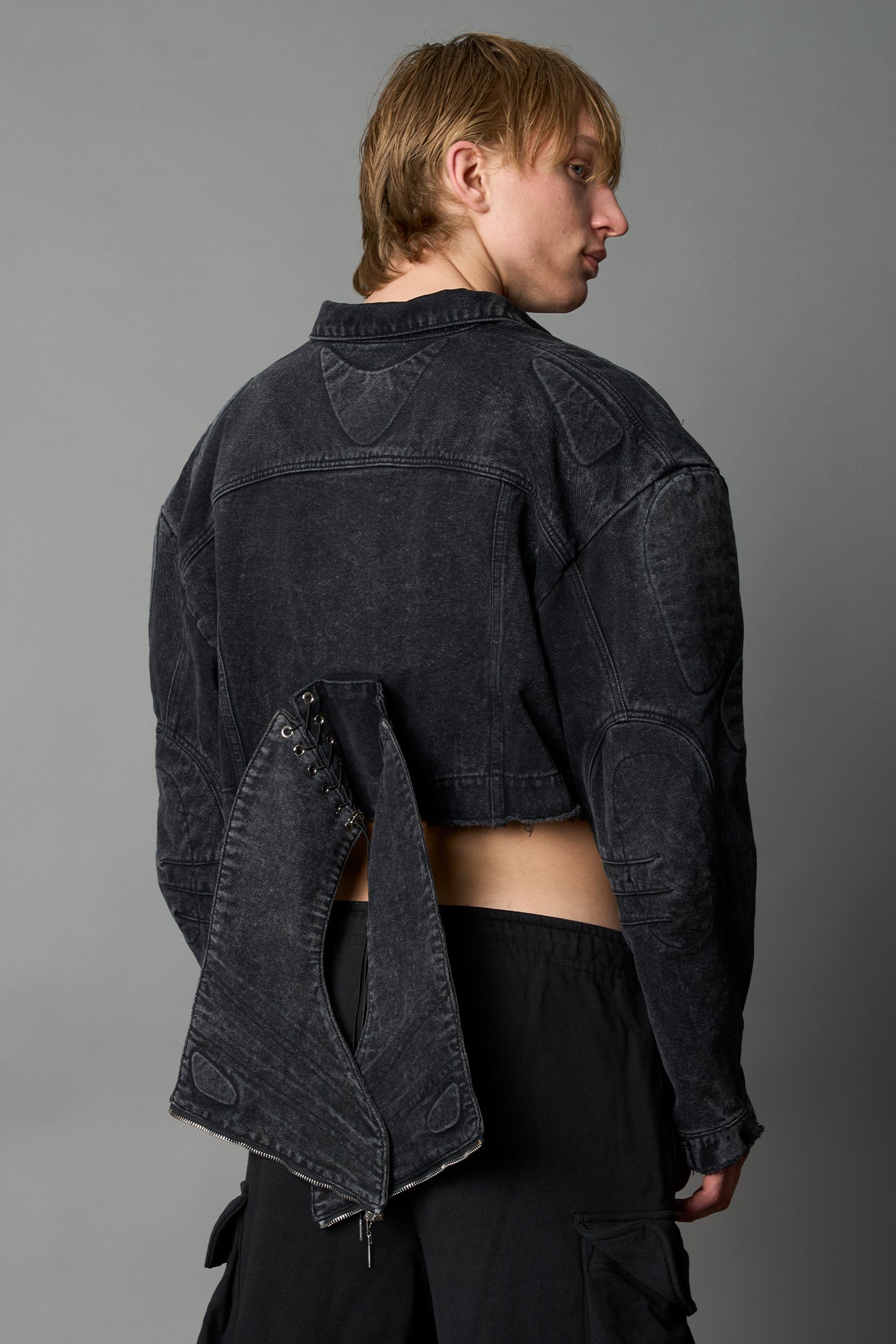 model wearing black washed denim jacket with structured corset waist and moto-style silhouette