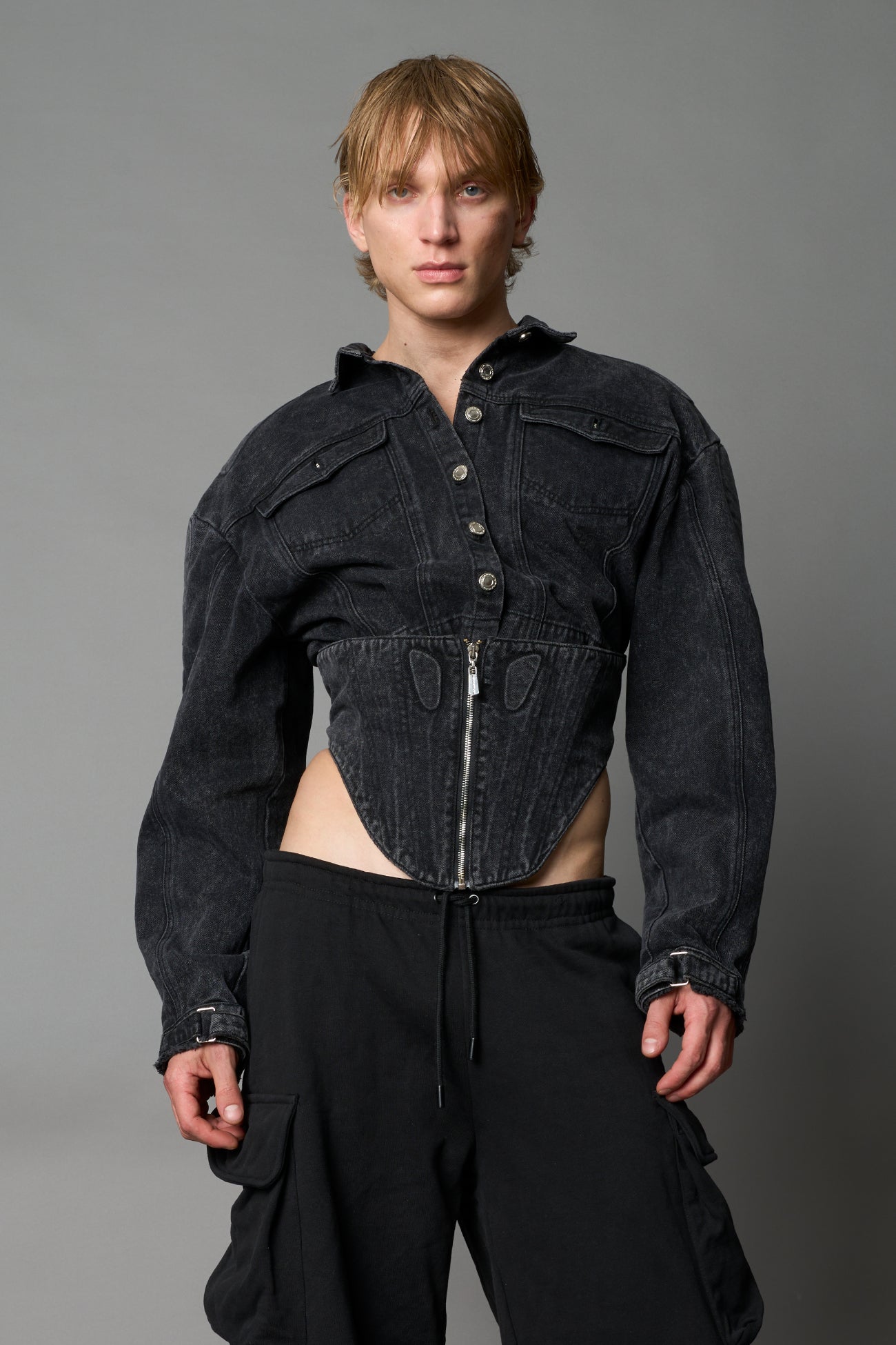 model wearing washed black denim jacket with structured corset waist and moto-style silhouette