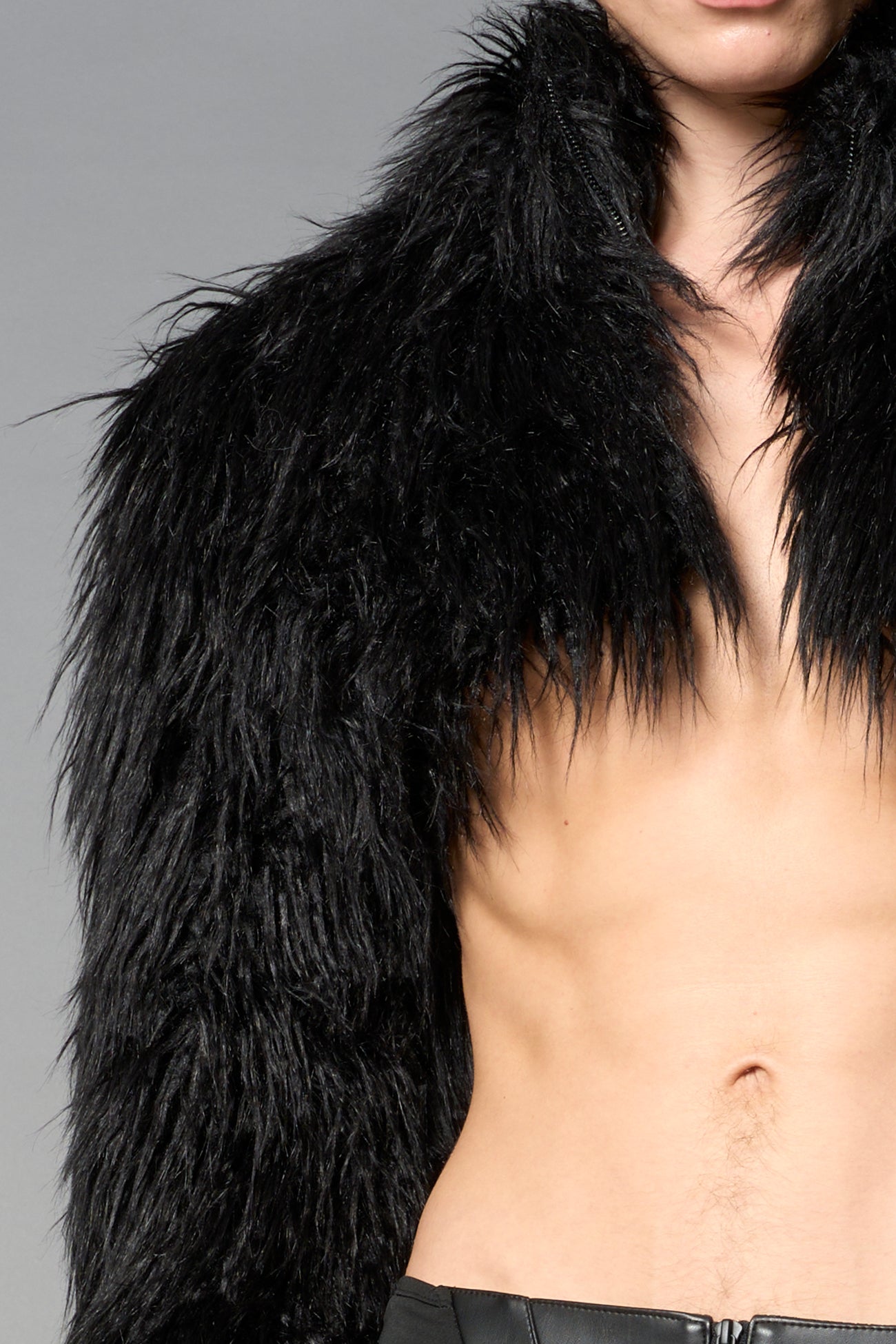 Black cropped faux fur jacket with exaggerated shoulders and high neck – bold statement outerwear for nightlife, streetwear, or runway looks.