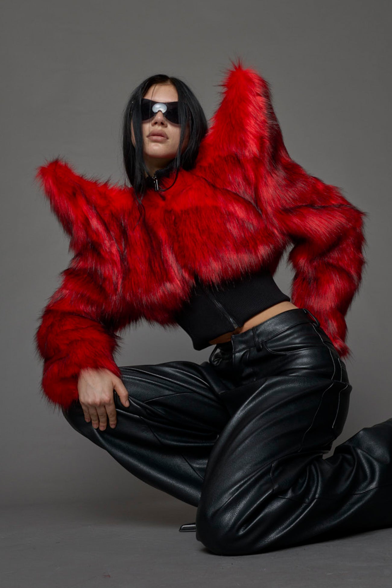 Model wearing red spike shoulder crop faux fur coat