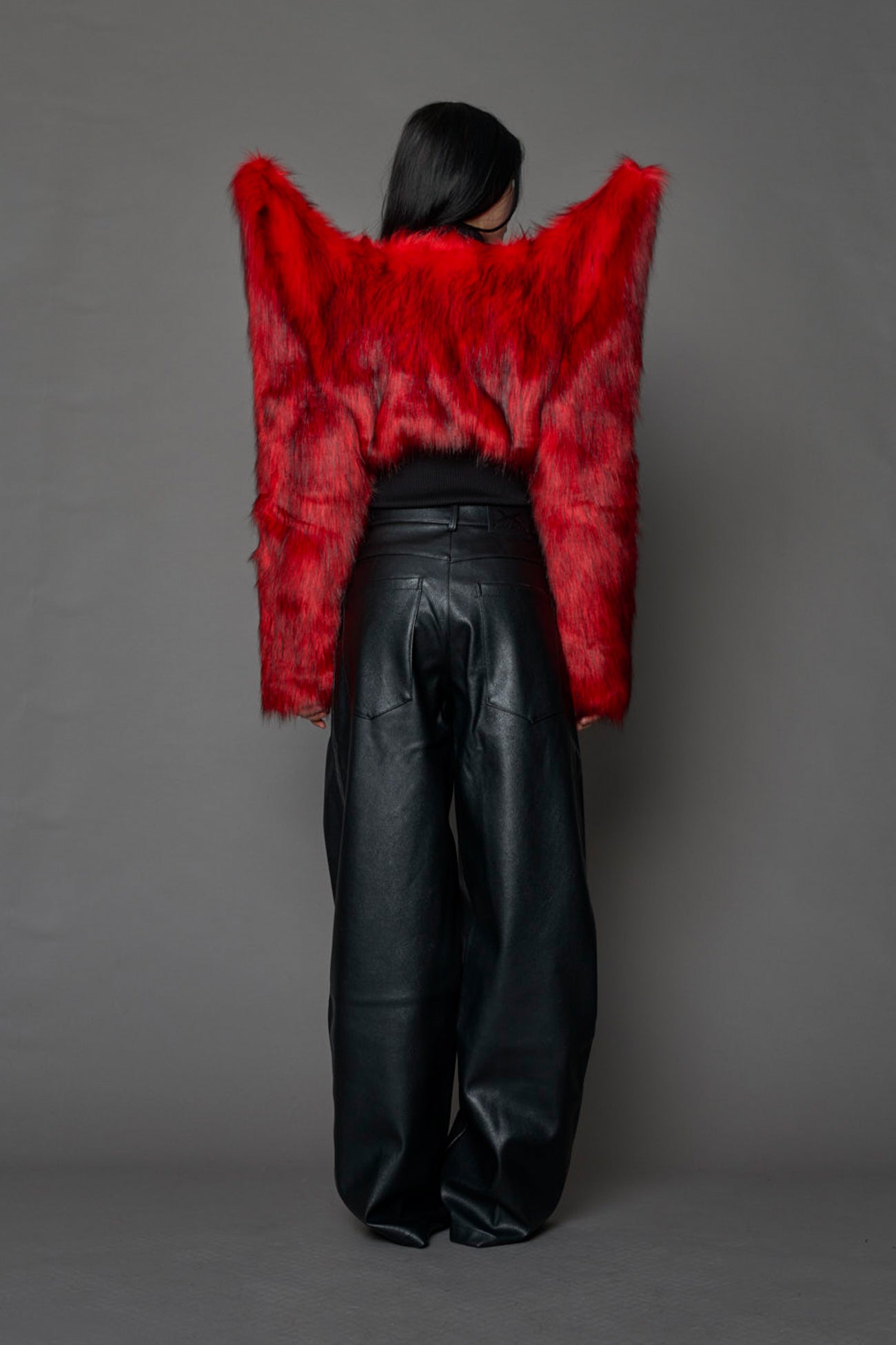 Model wearing red spike shoulder crop faux fur coat