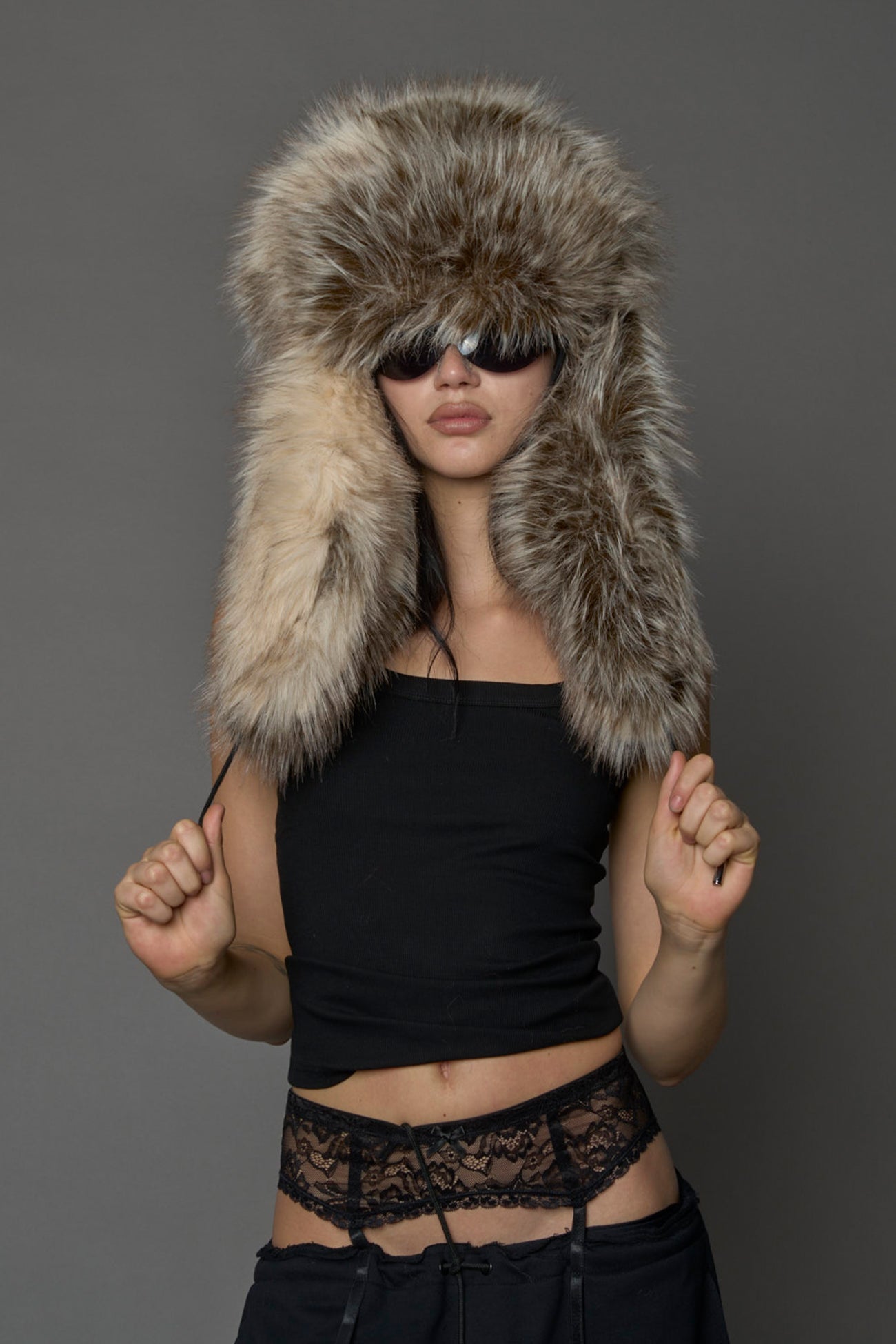 Model wearing oversized brown and cream faux-fur hood hat with drawstrings