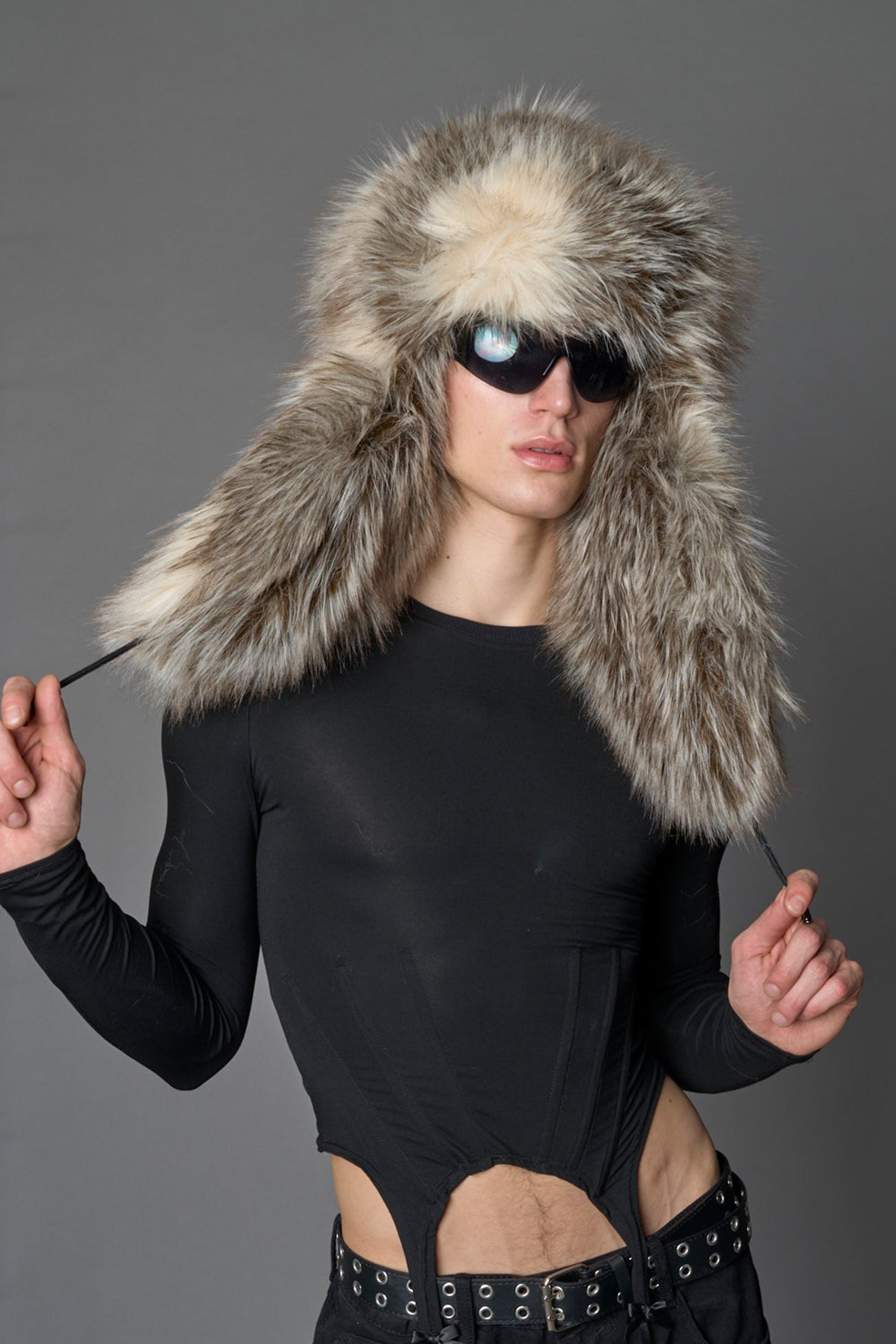 Model wearing oversized brown and cream faux-fur hood hat with drawstrings