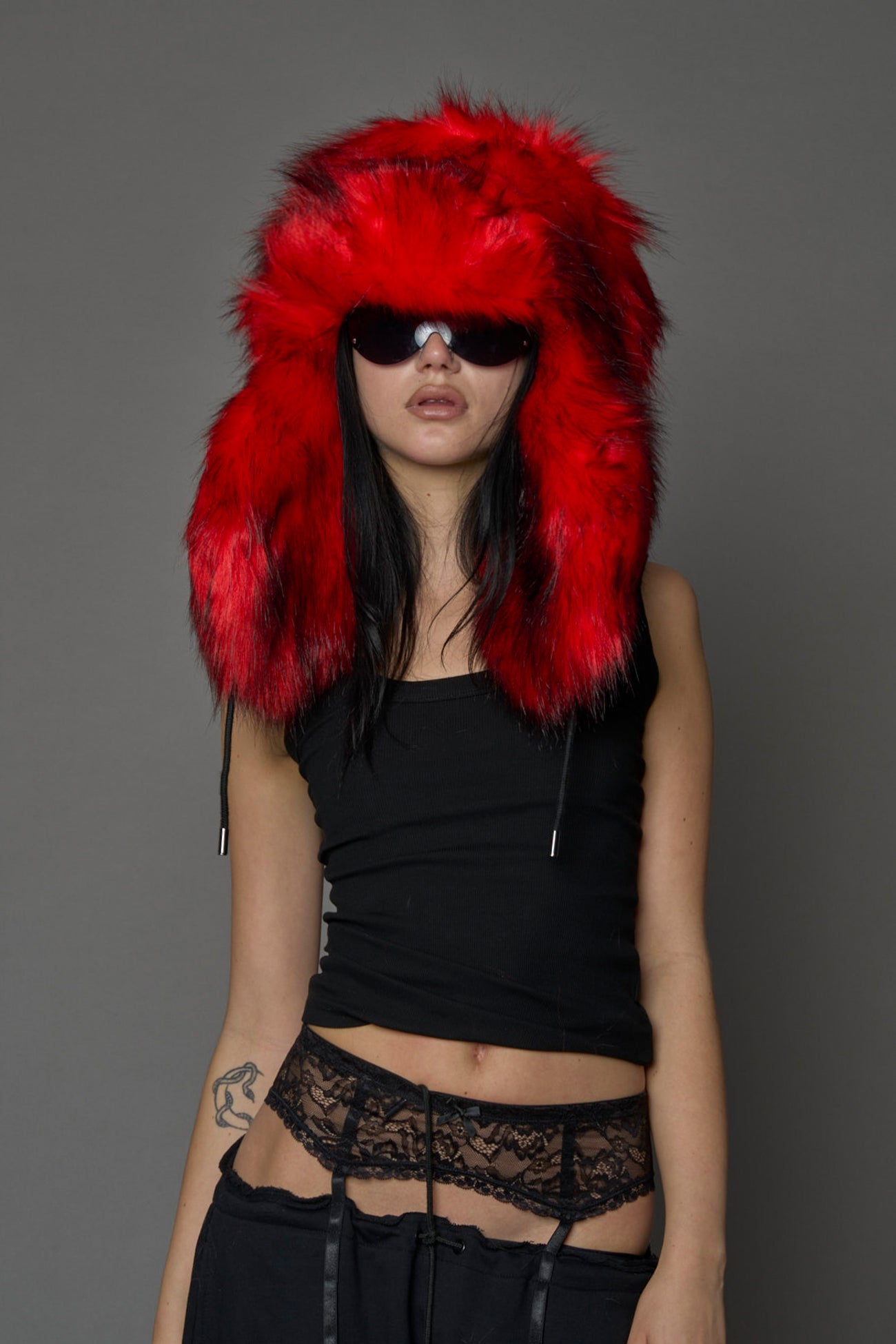 Model wearing oversized red and cream faux-fur hood hat with drawstrings