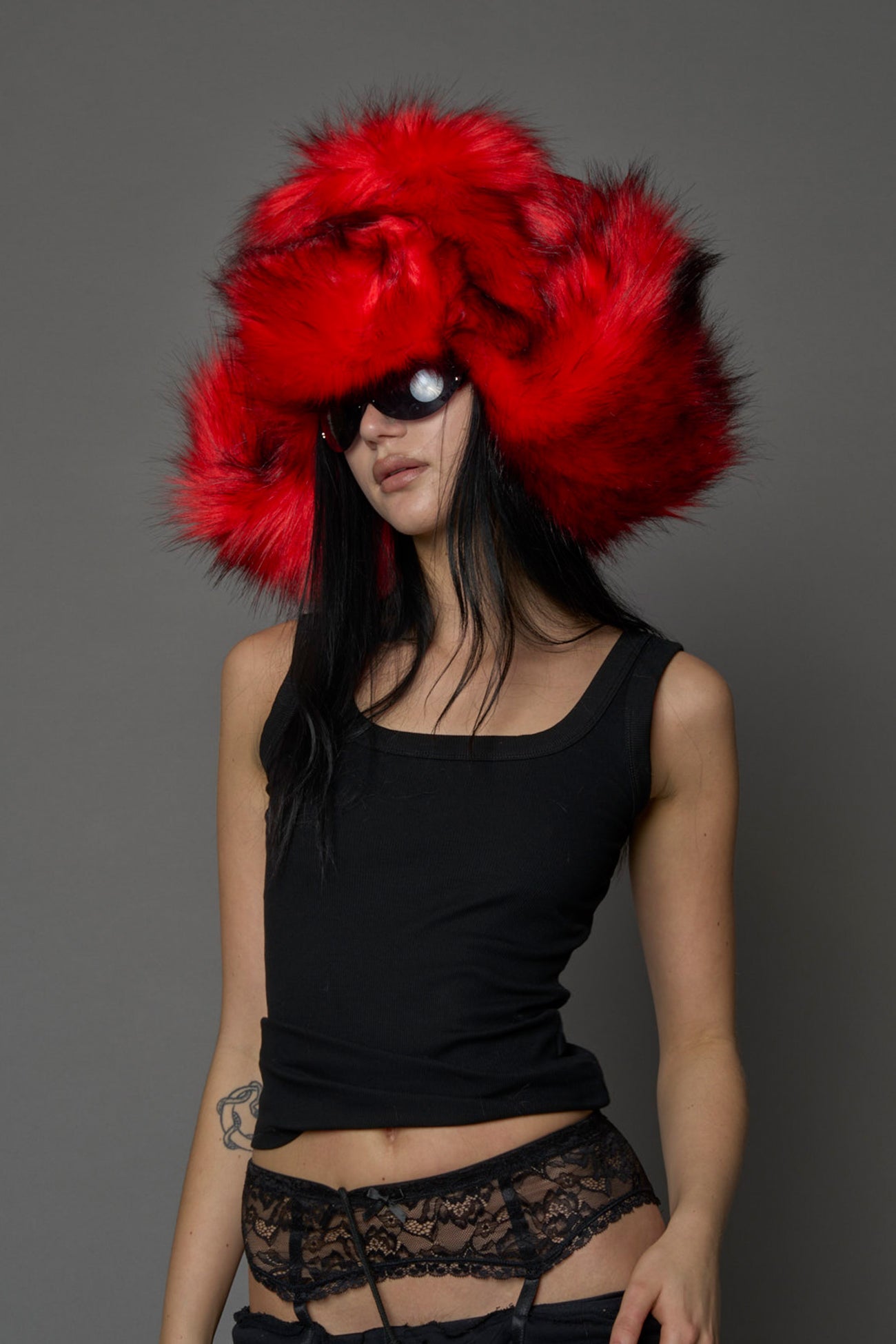 Model wearing oversized red and cream faux-fur hood hat with drawstrings