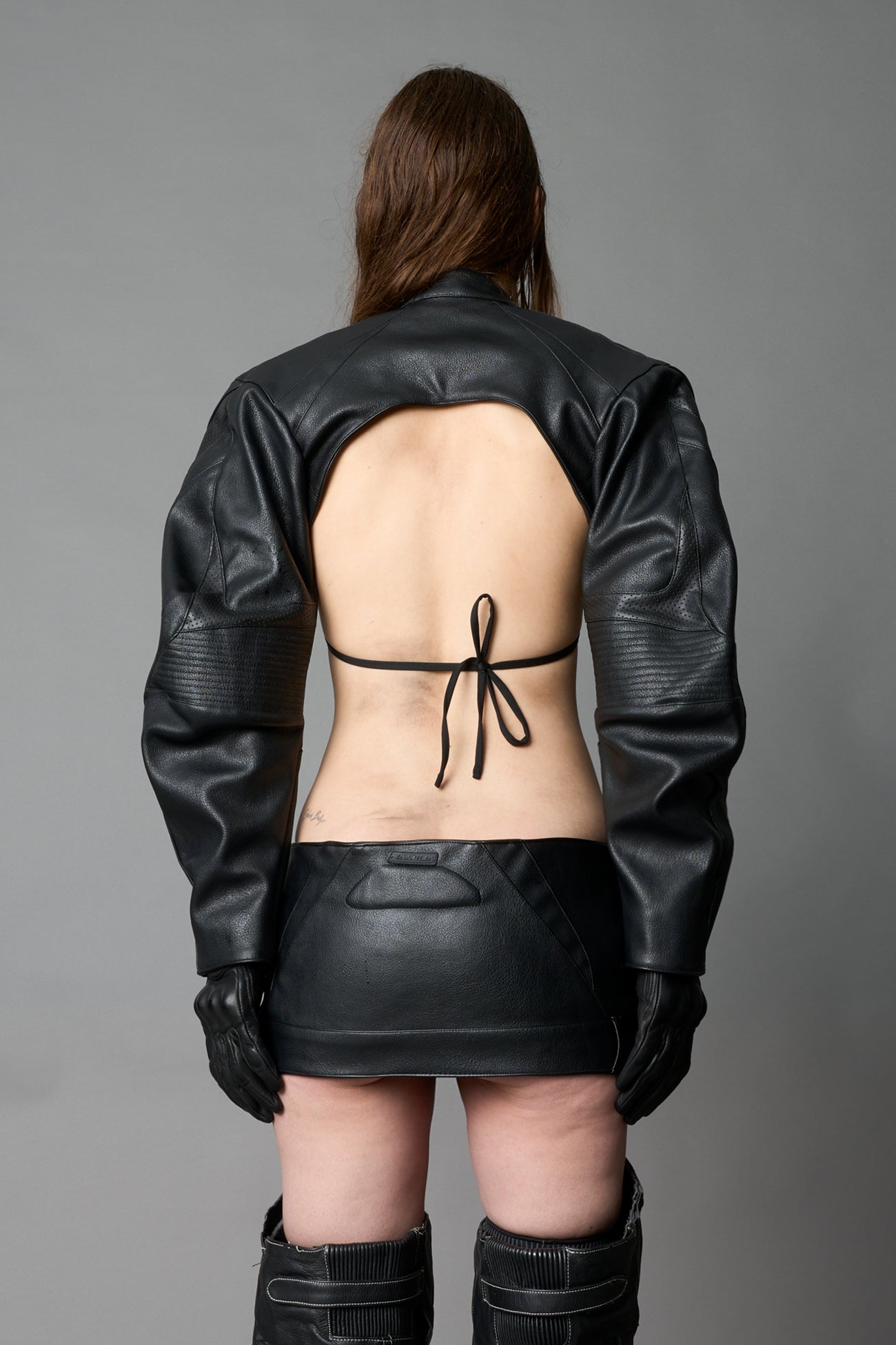 Model wearing a black vegan leather cropped jacket with a high choker collar and zipper front
