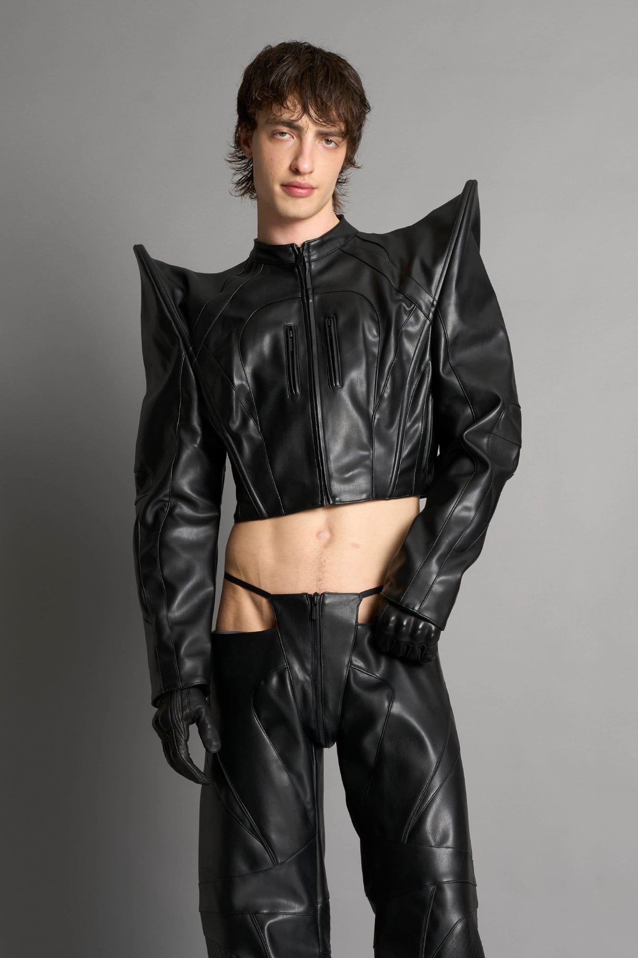 Model wears the black Namilia Spike Moto Jacket with wire shoulder pads, branded zipper, band collar, zippered breast and waist pockets, motocross-style lines, and black logo rubber tag on the back.