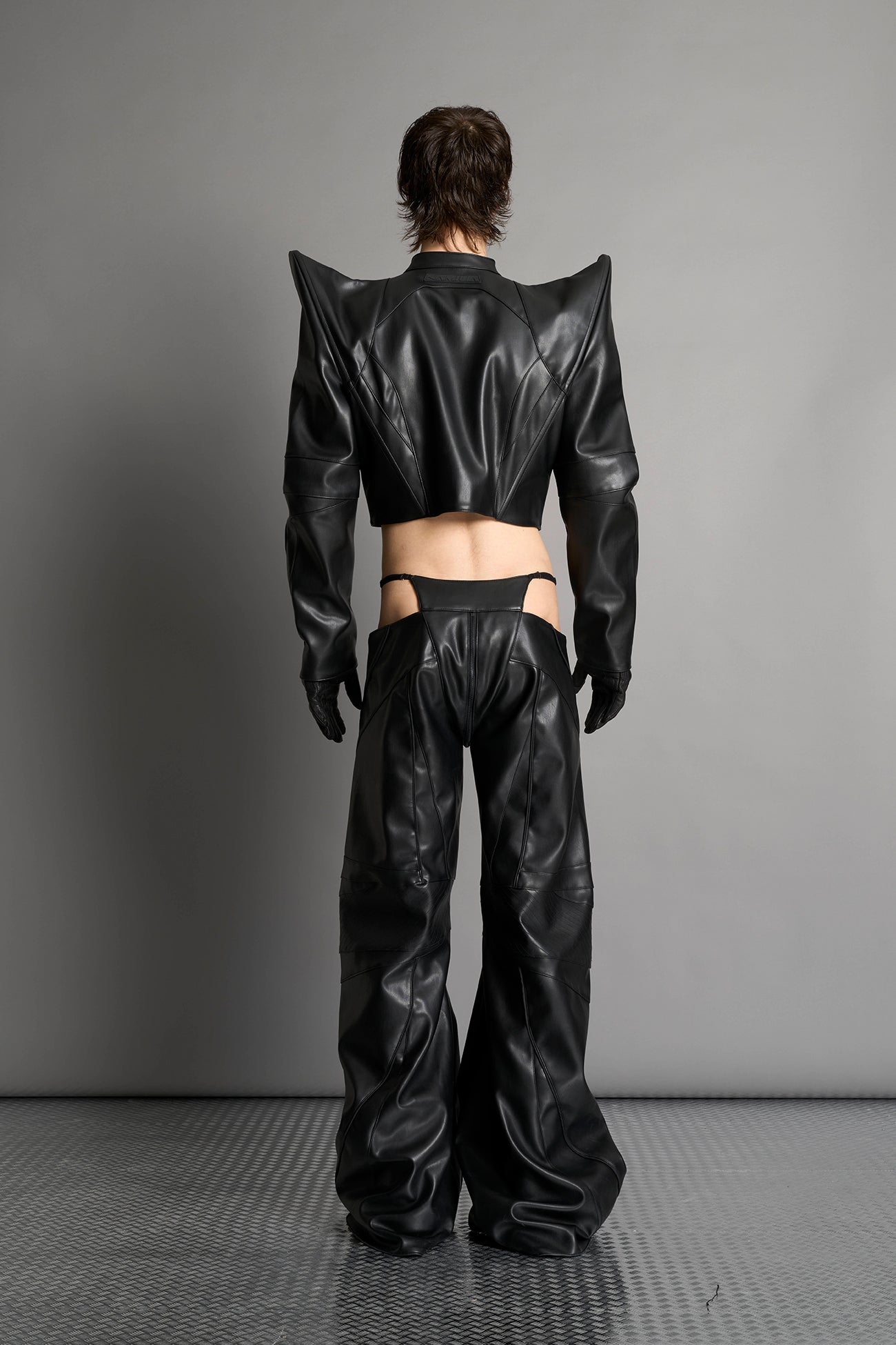 Model wears the black Namilia Spike Moto Jacket with wire shoulder pads, branded zipper, band collar, zippered breast and waist pockets, motocross-style lines, and black logo rubber tag on the back.
