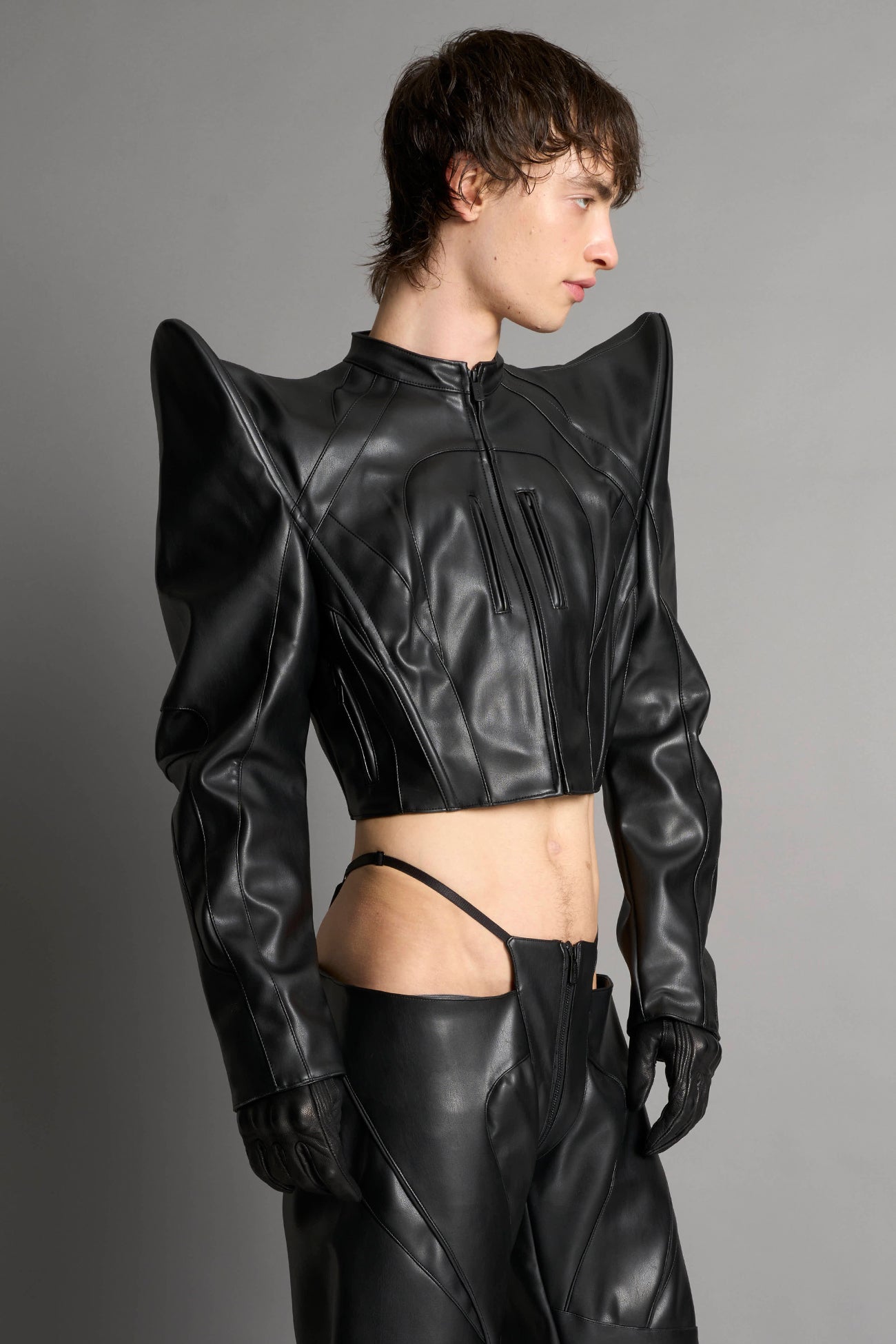 Model wears the black Namilia Spike Moto Jacket with wire shoulder pads, branded zipper, band collar, zippered breast and waist pockets, motocross-style lines, and black logo rubber tag on the back.