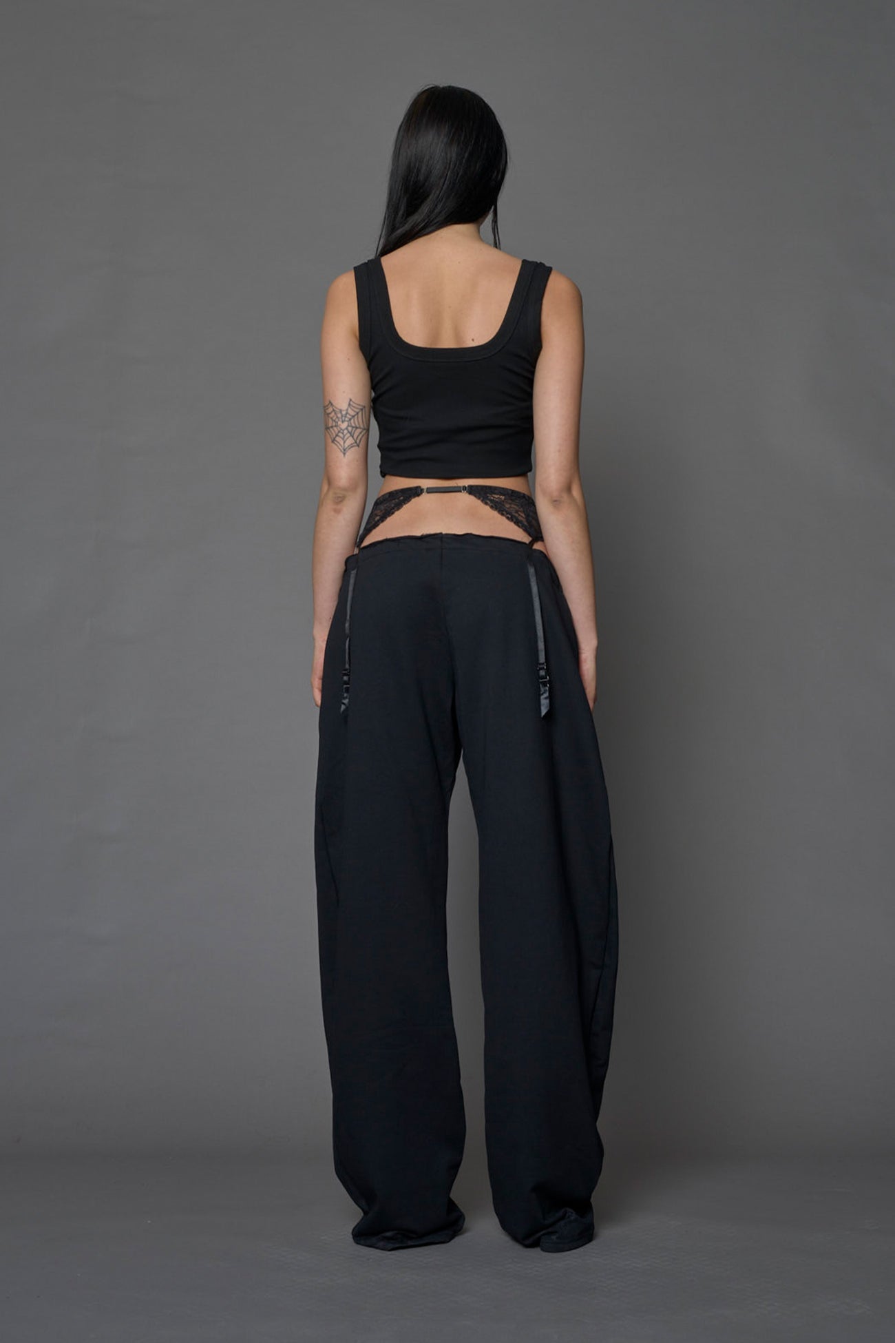female model wearing a black low waist jogger with a lace suspender belt