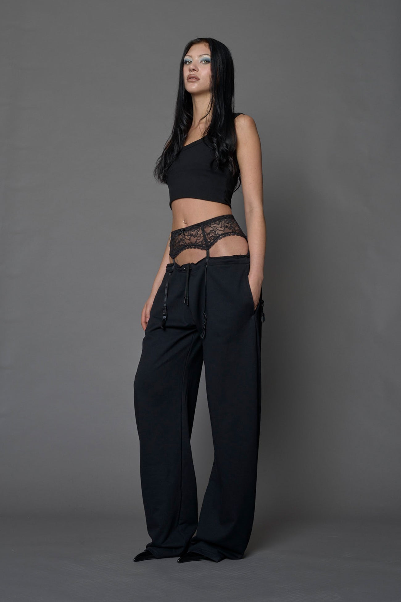 female model wearing a black low waist jogger with a lace suspender belt