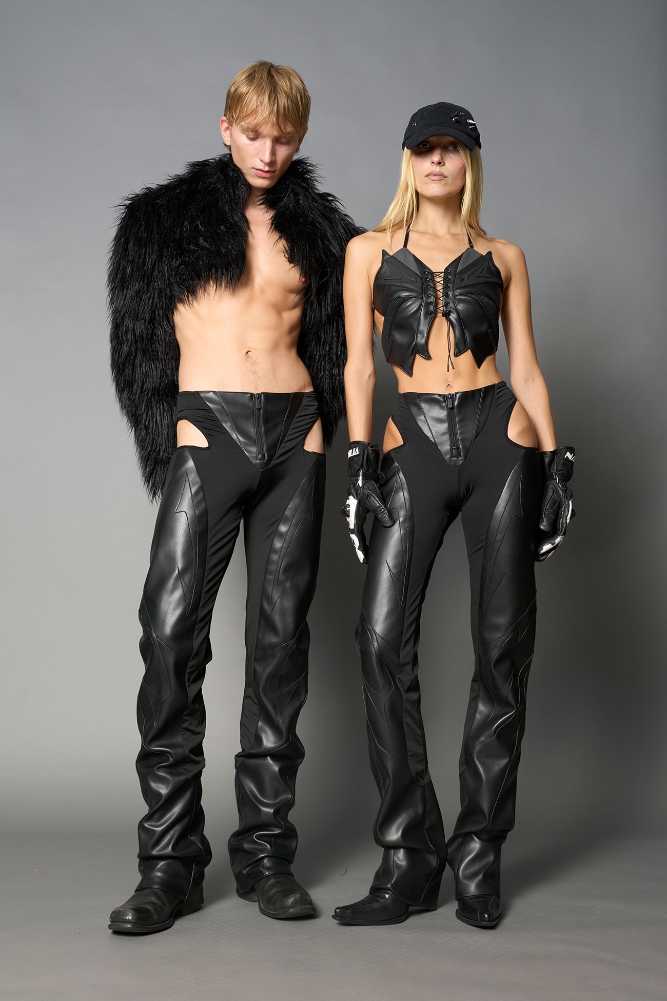 Black cut-out flare pants with graphic details, vegan leather panels, and low-rise waist – edgy motocross-inspired trousers for men’s streetwear or festival looks.