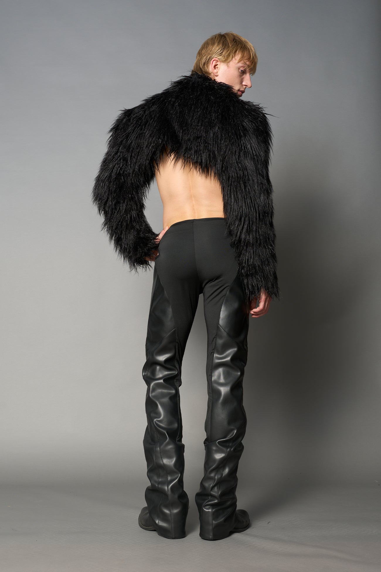 Black cut-out flare pants with graphic details, vegan leather panels, and low-rise waist – edgy motocross-inspired trousers for men’s streetwear or festival looks.