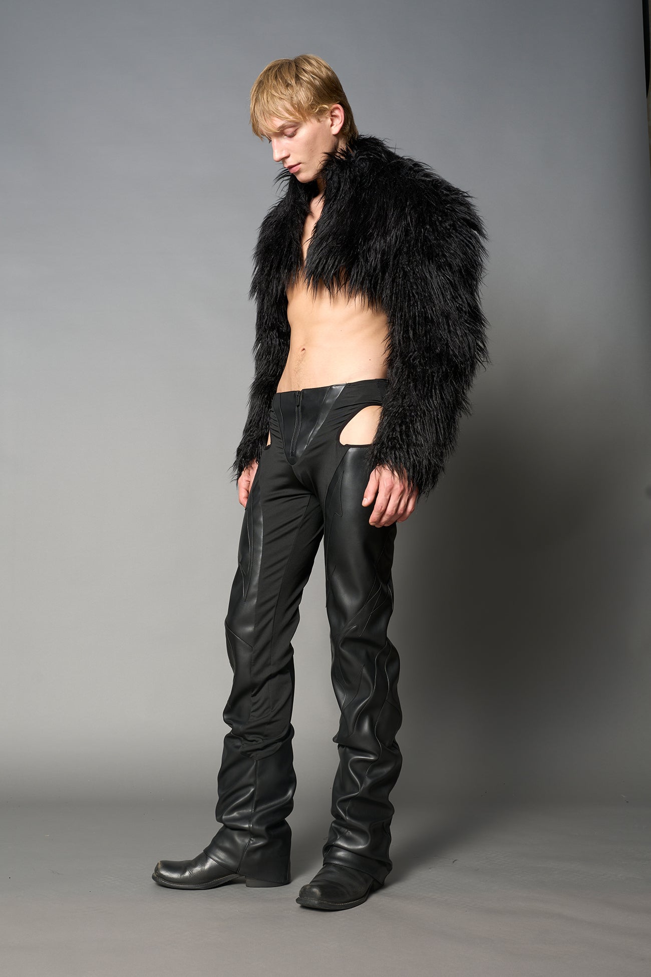 Black cut-out flare pants with graphic details, vegan leather panels, and low-rise waist – edgy motocross-inspired trousers for men’s streetwear or festival looks.