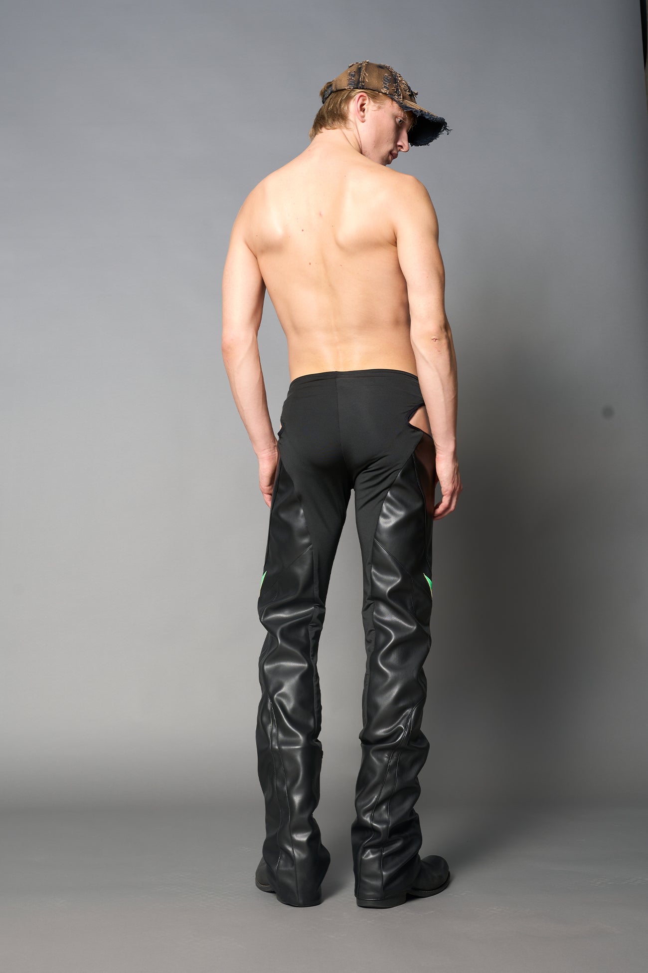 Green cut-out flare pants with graphic details, vegan leather panels, and low-rise waist – edgy motocross-inspired trousers for men’s streetwear or festival looks.