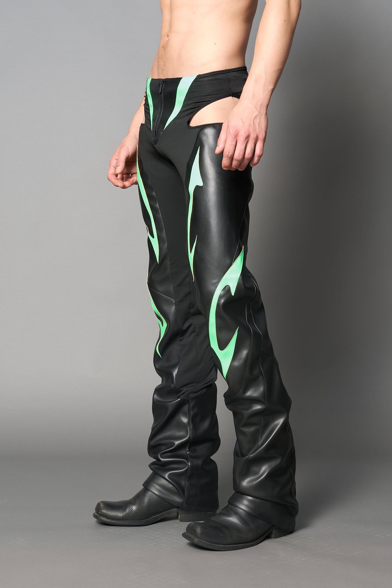 Green cut-out flare pants with graphic details, vegan leather panels, and low-rise waist – edgy motocross-inspired trousers for men’s streetwear or festival looks.